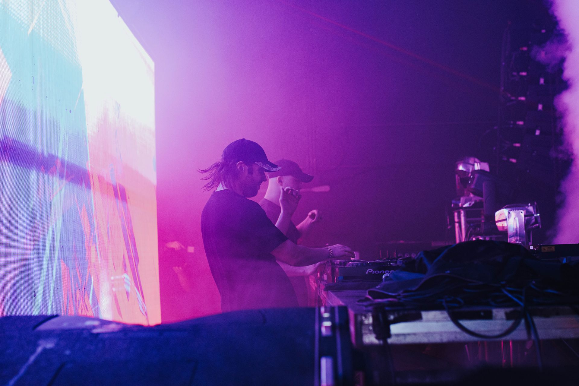 A man is singing into a microphone on a stage in front of a large screen.