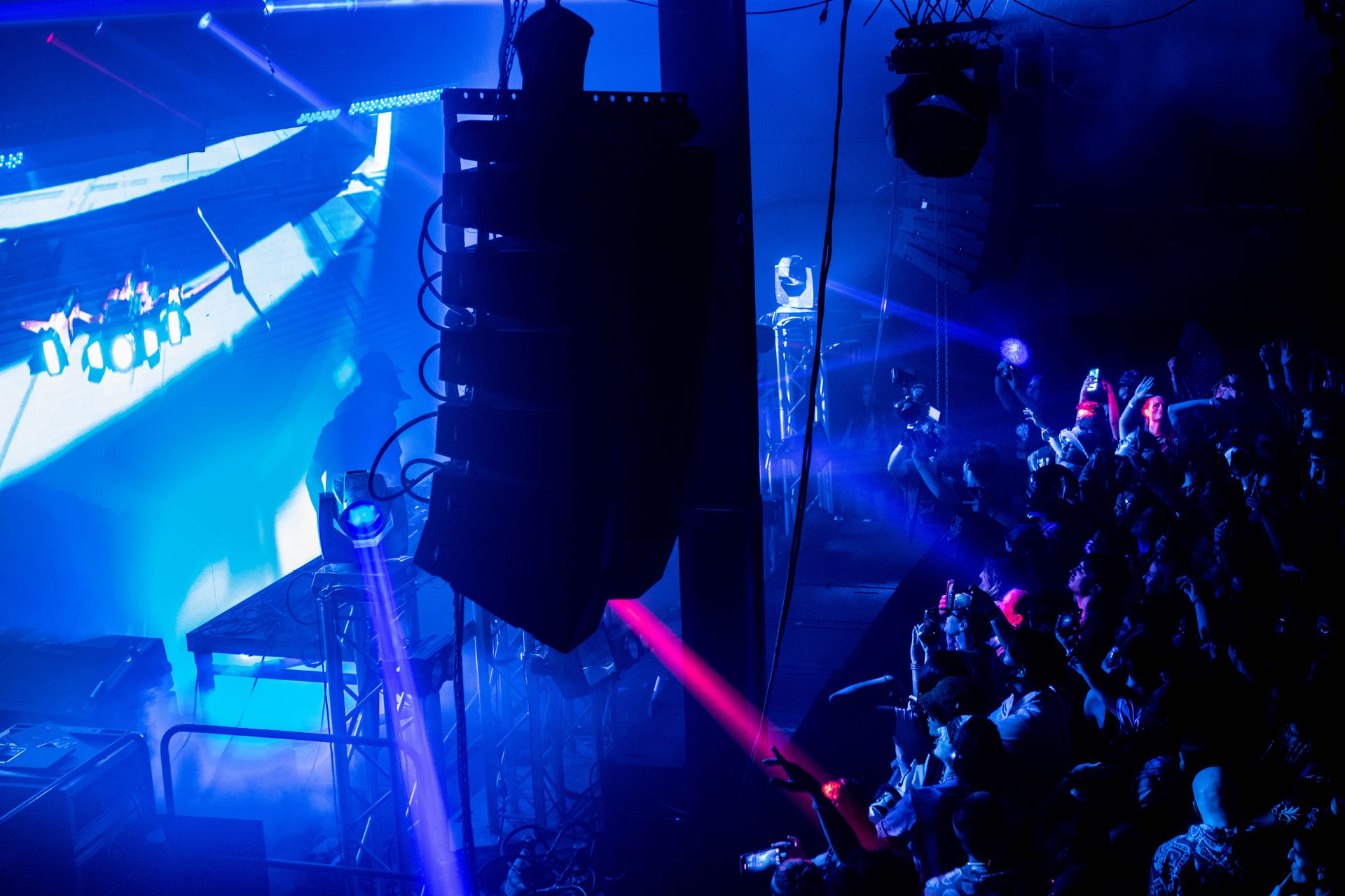 A crowd of people are watching a concert in a dark room.