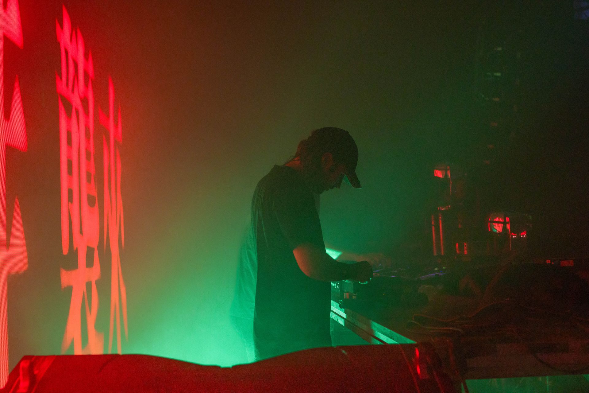 A man is playing a dj set in a dark room.