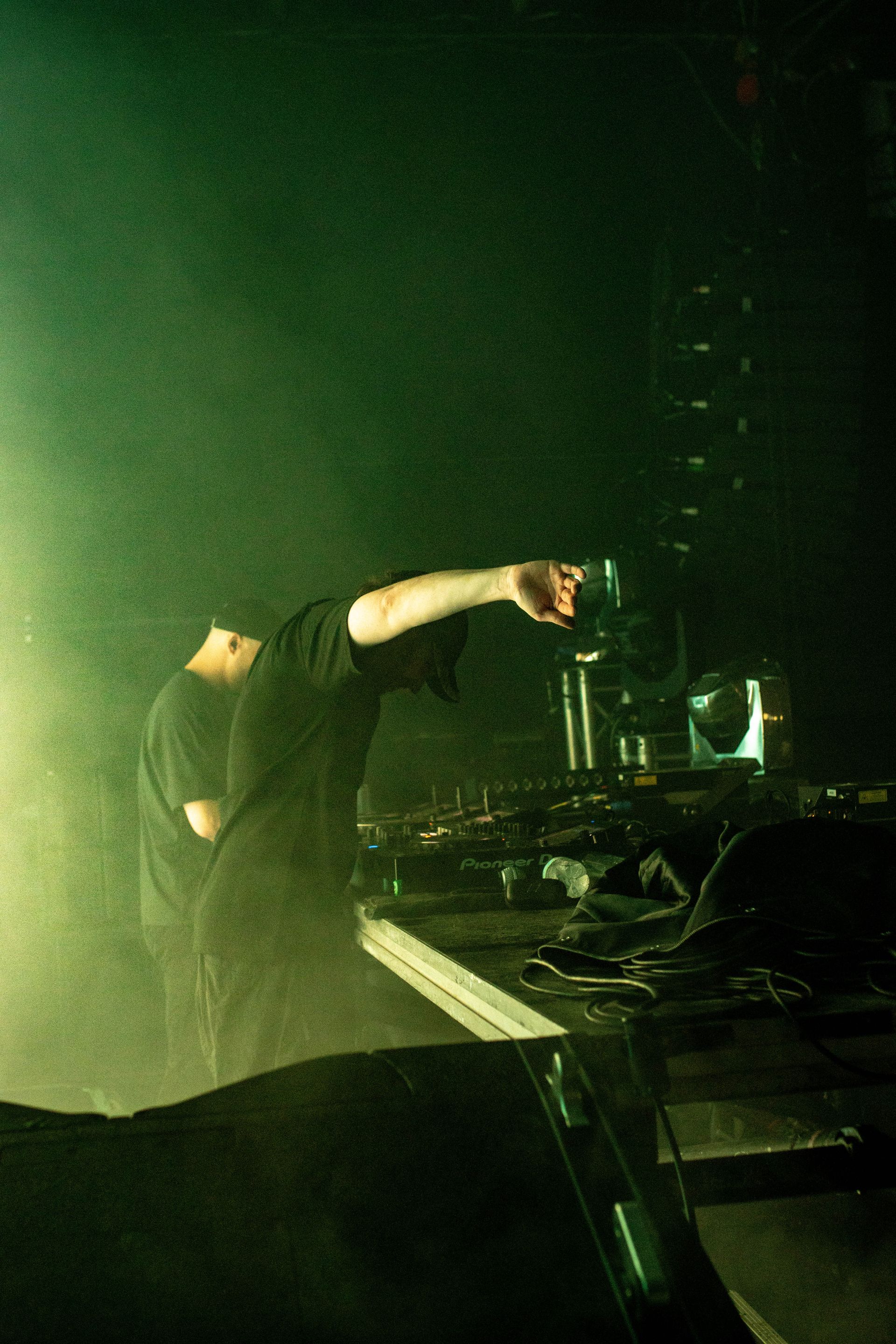 A man is standing in front of a piano in a dark room.