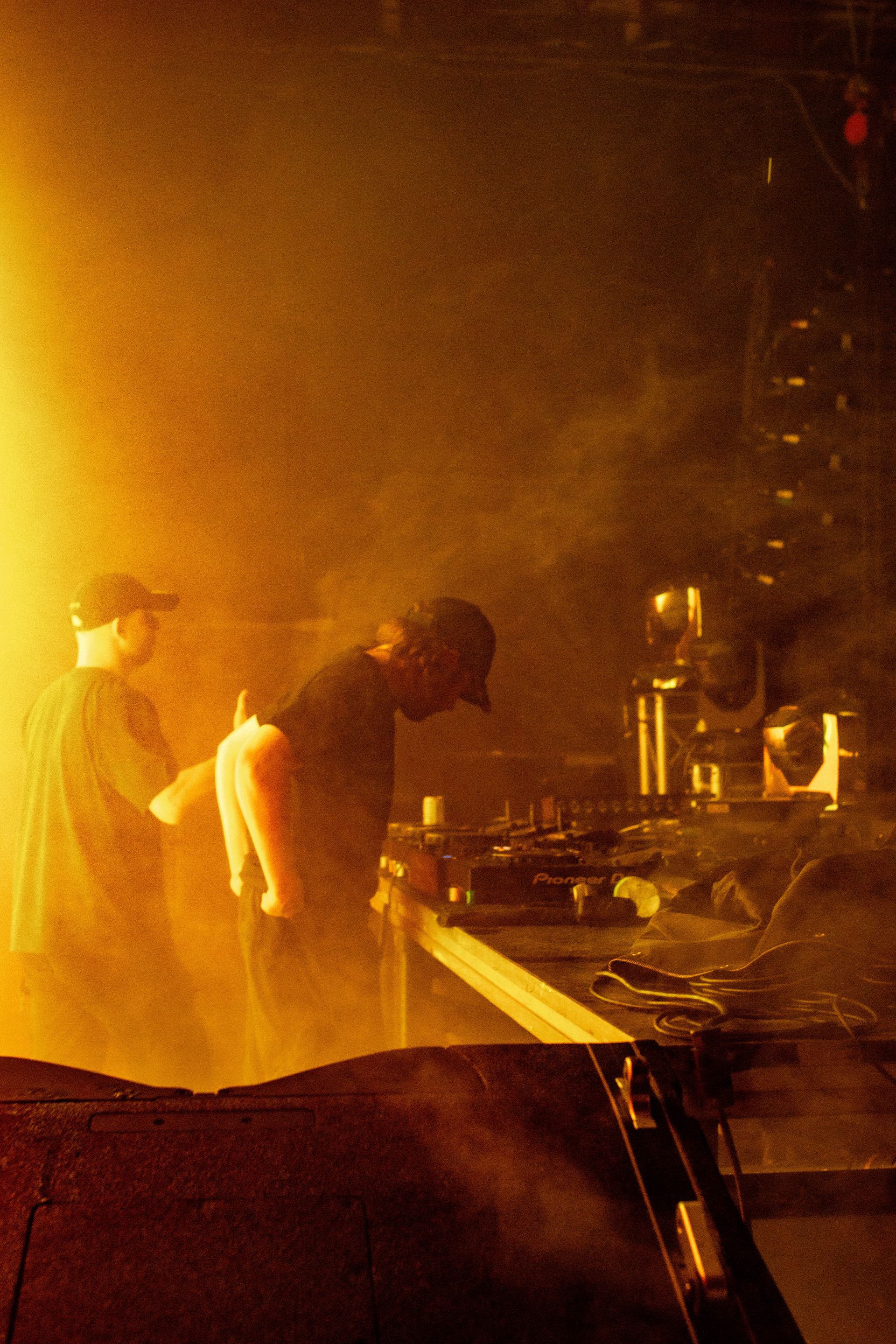 A man is standing in front of a table in a dark room with smoke coming out of it.