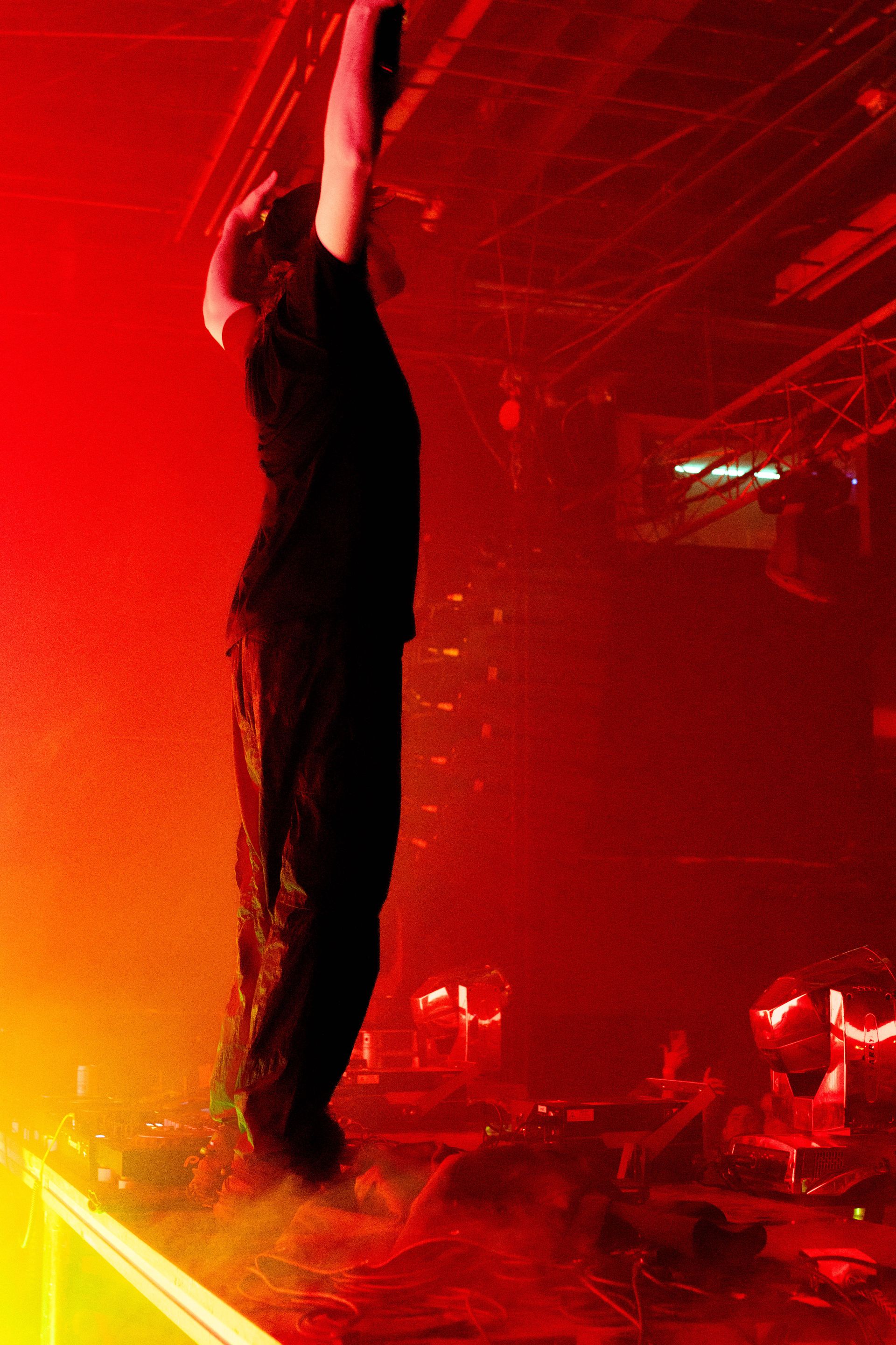 A man is standing on a stage with his arms in the air.