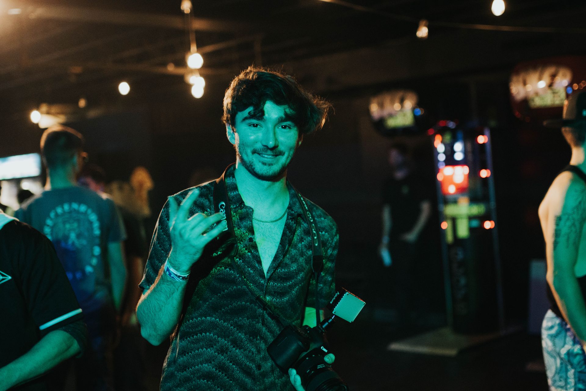 A man is standing in a dark room with a camera in his hand.