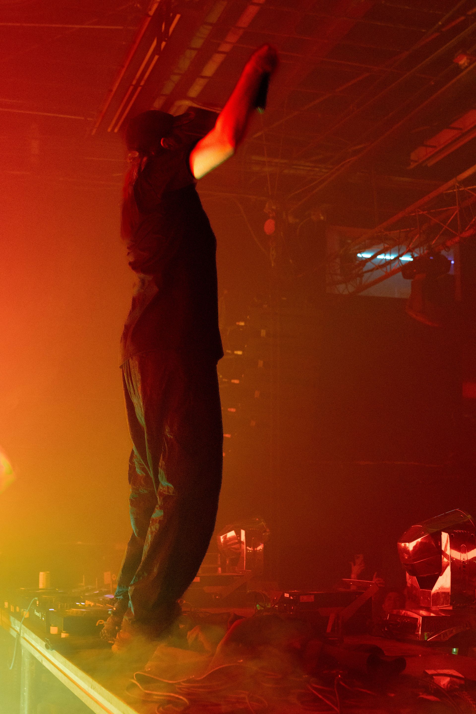 A man is singing into a microphone on a stage in a dark room.