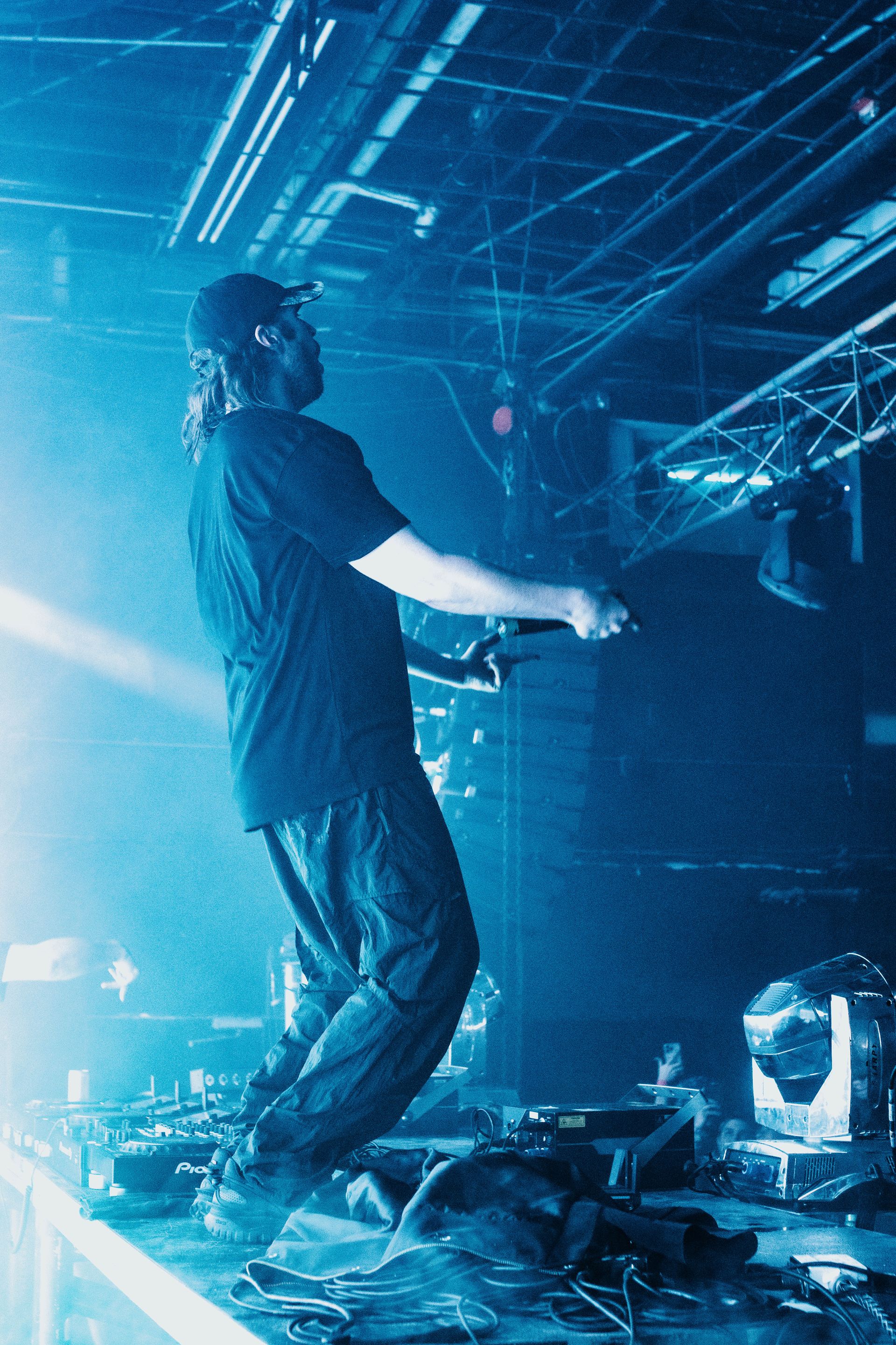 A man is singing into a microphone on a stage in a dark room.