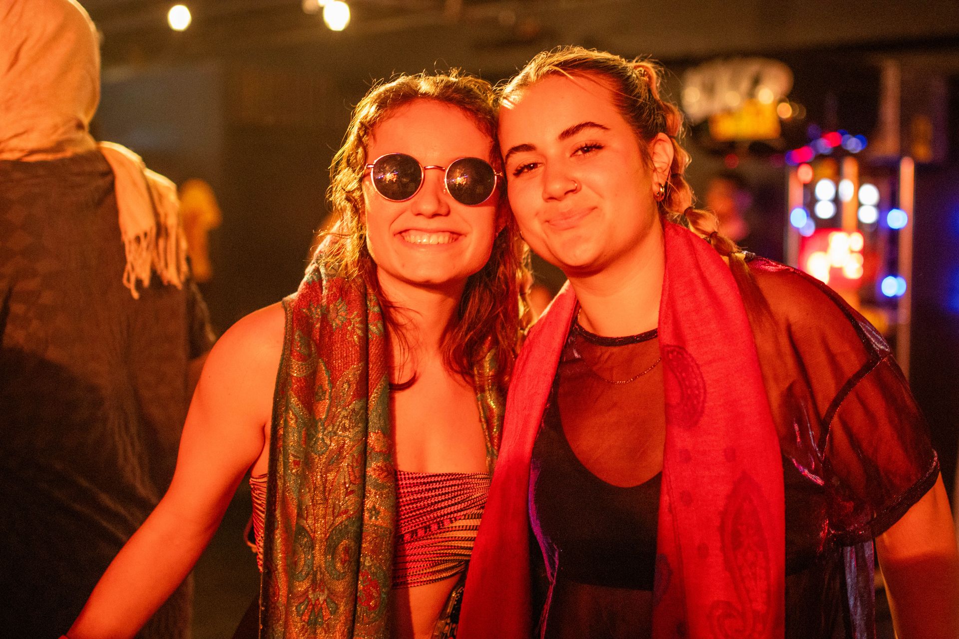 Two women wearing sunglasses and scarves are posing for a picture.