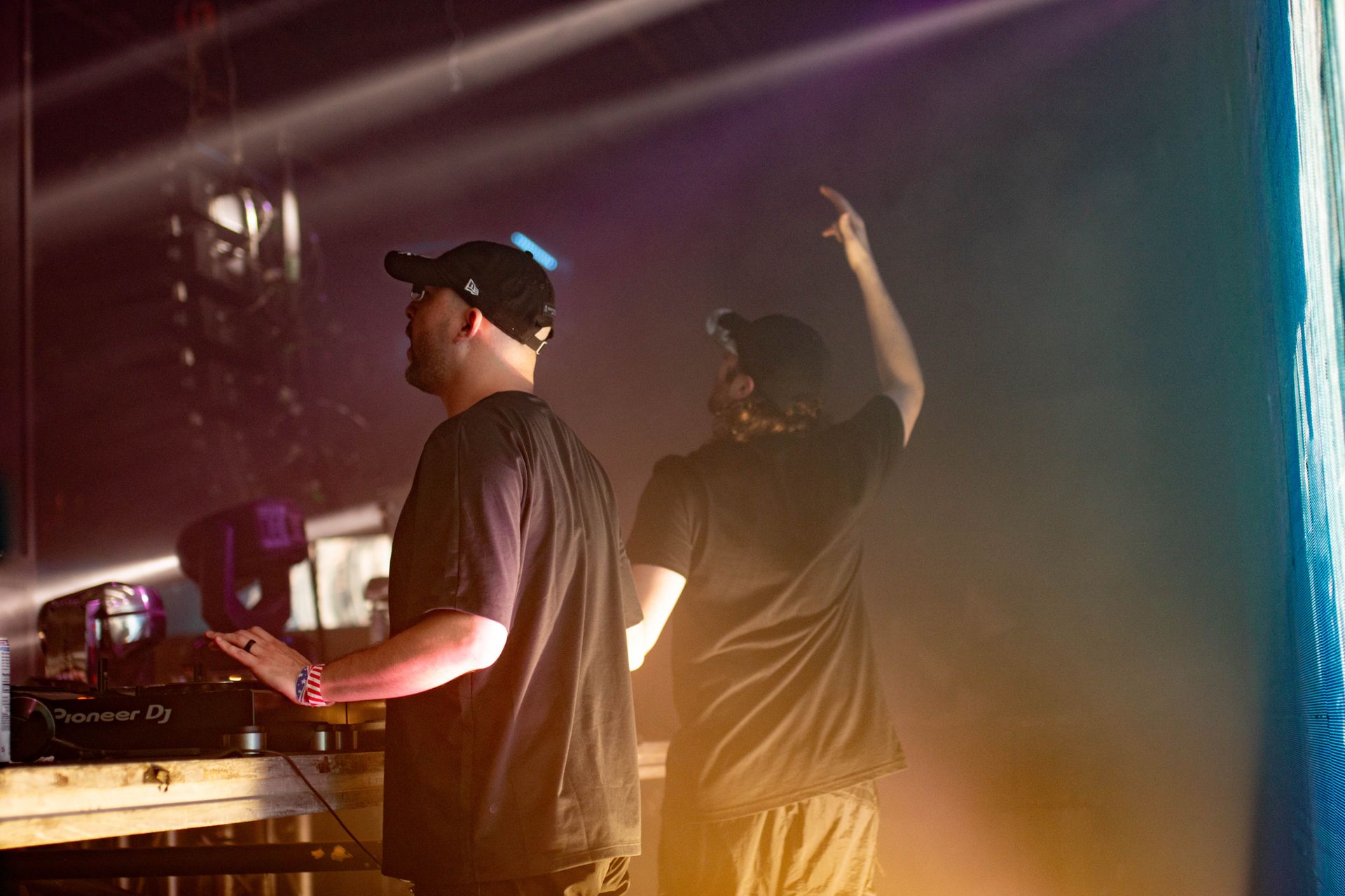 Two men are standing next to each other on a stage in a dark room.