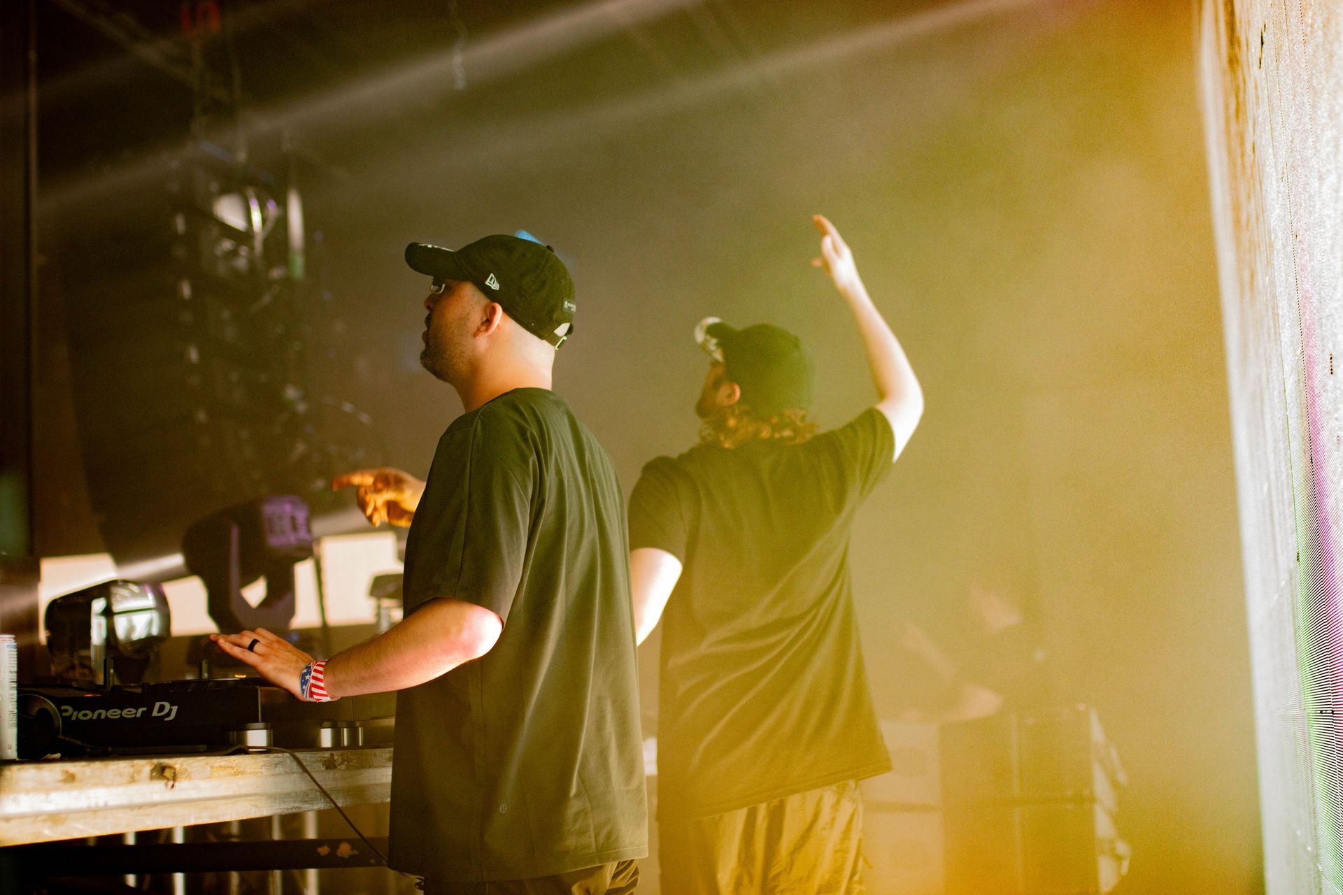 Two men are standing next to each other on a stage with their arms in the air.