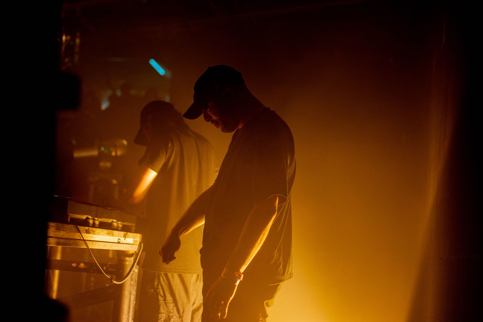 Two men are standing next to each other in a dark room.