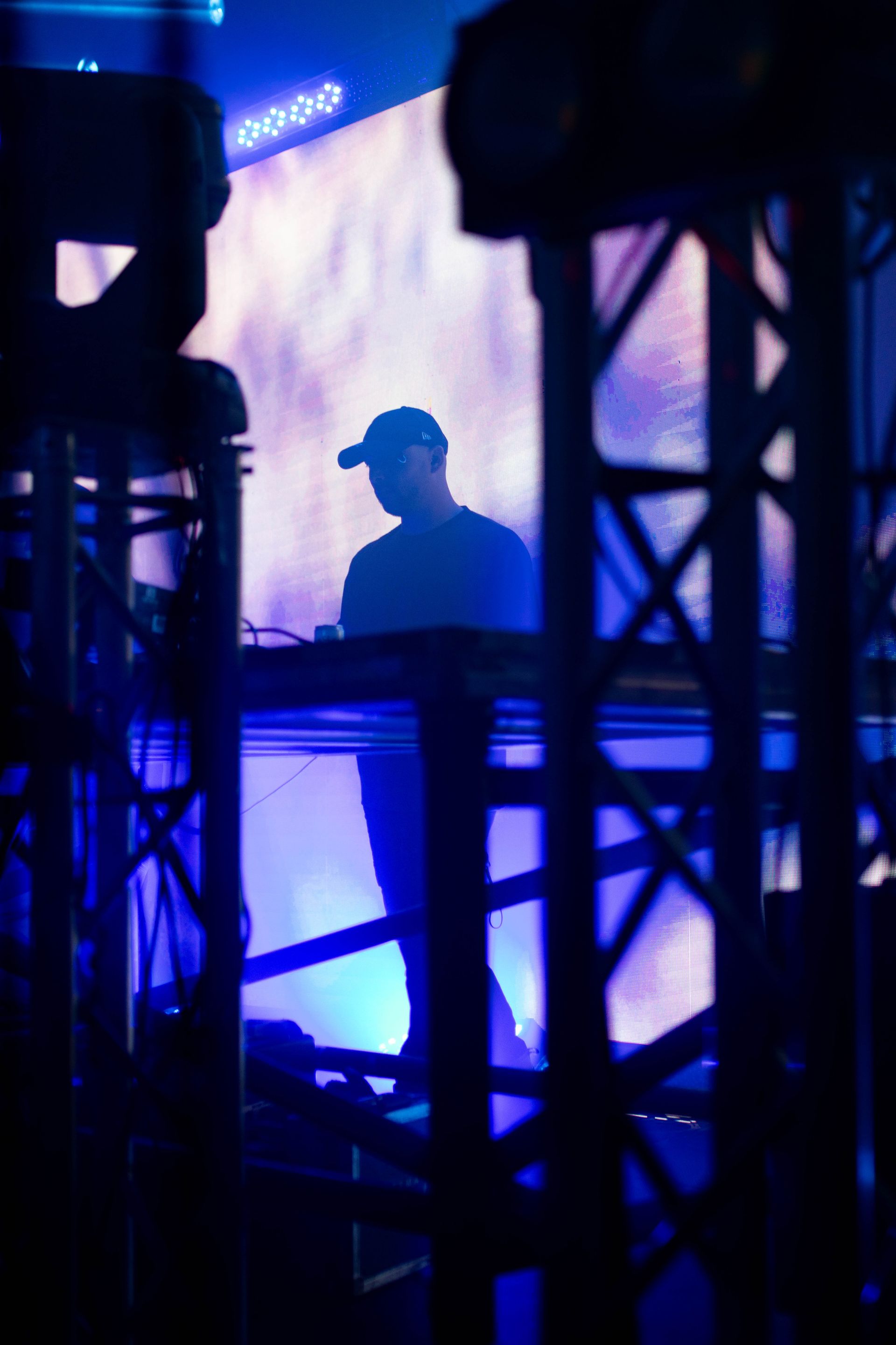 A man in a hat is standing in front of a large screen.