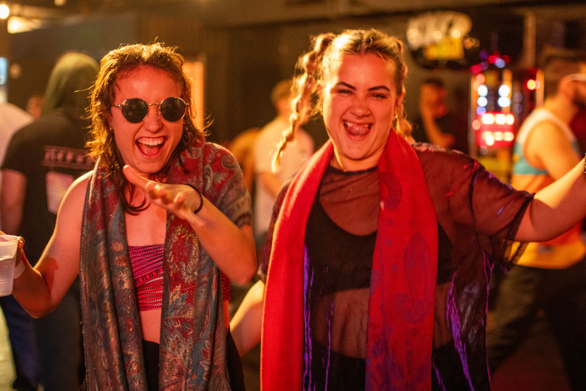 Two women are standing next to each other at a party and laughing.