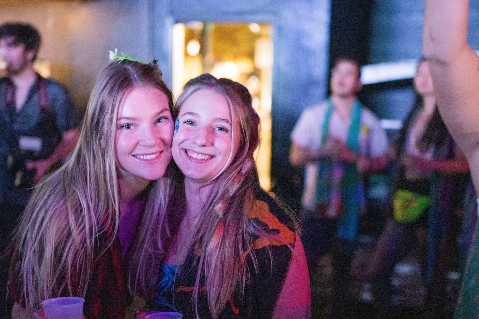 Two young women are posing for a picture at a party.