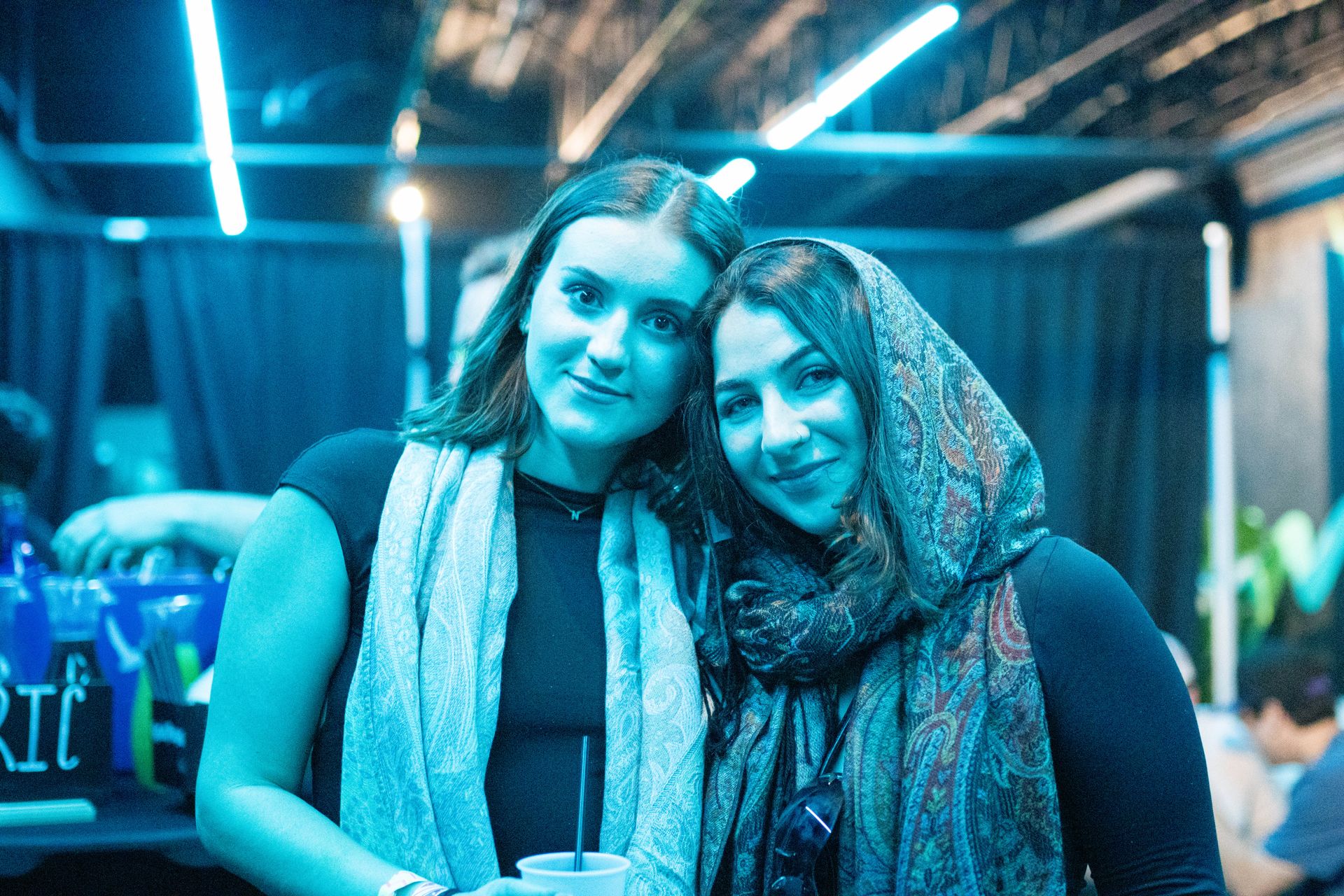 Two women are posing for a picture together in a dark room.