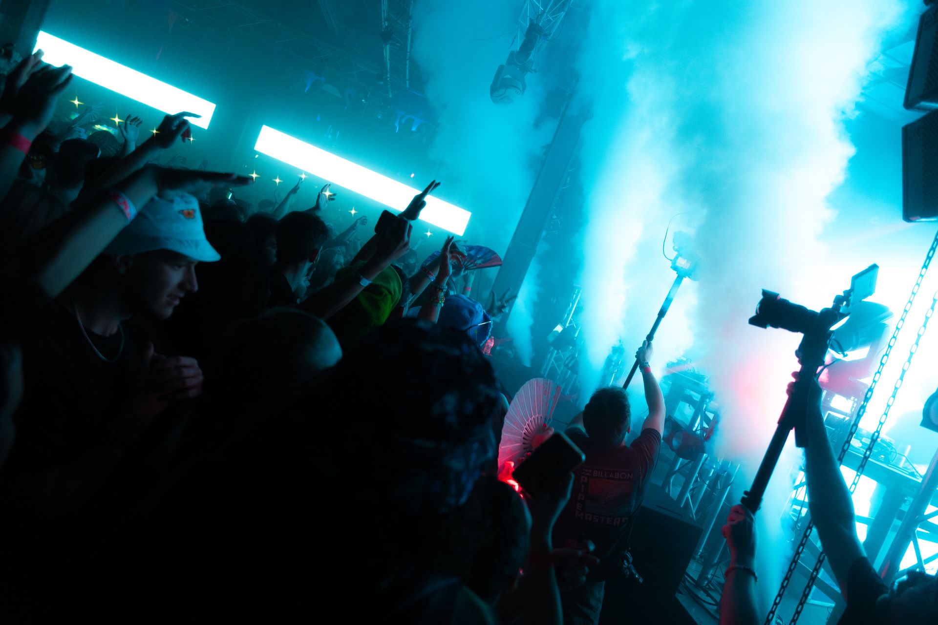 A crowd of people at a concert with smoke coming out of the stage