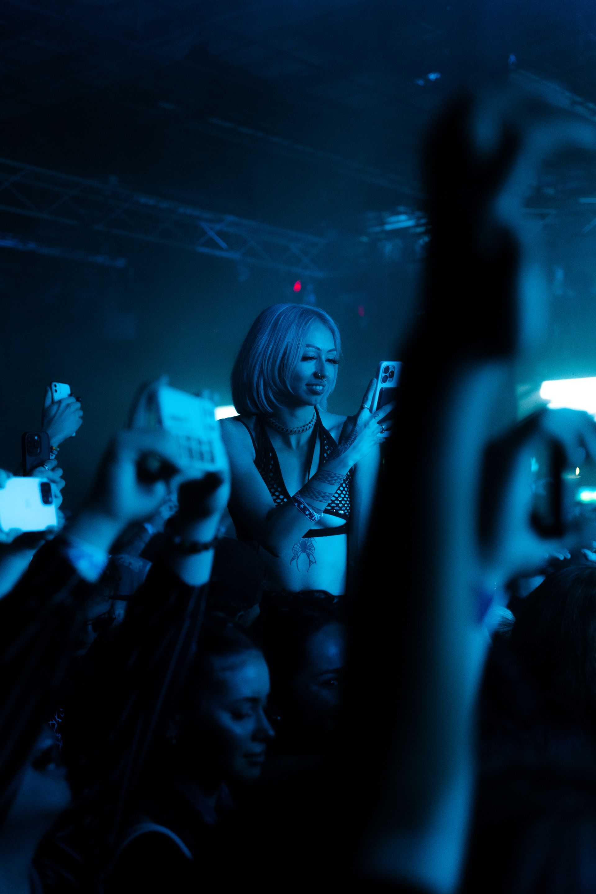 A woman is taking a picture of a crowd of people at a concert.