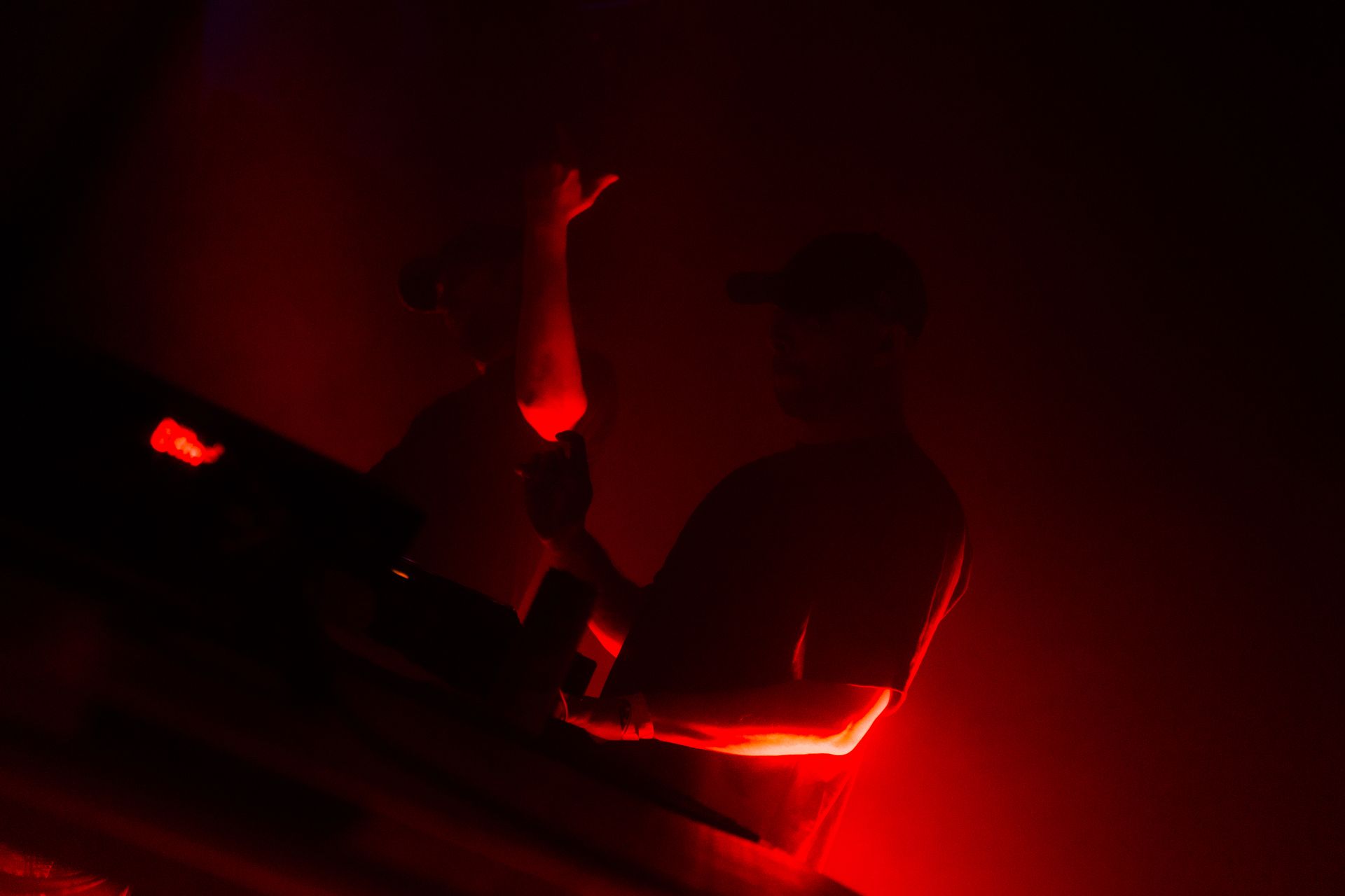 A man is playing a guitar in a dark room with red lights.