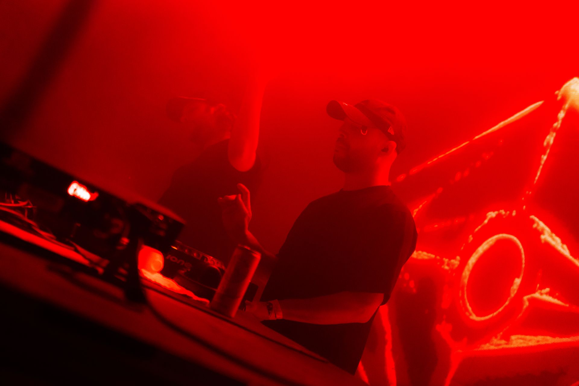 A man is sitting at a table in a dark room in front of a red light.