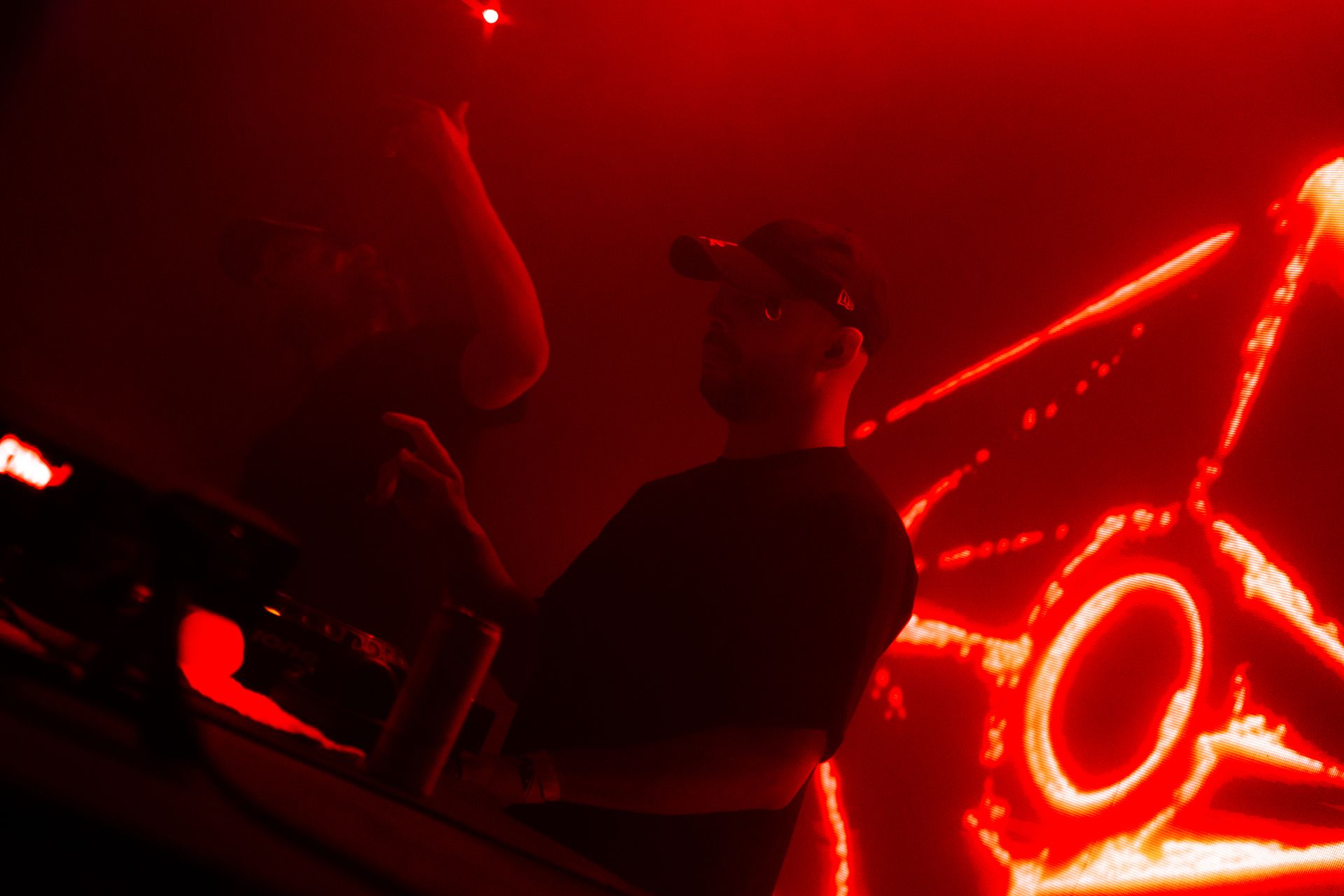 A person is playing a video game in a dark room with red lights.