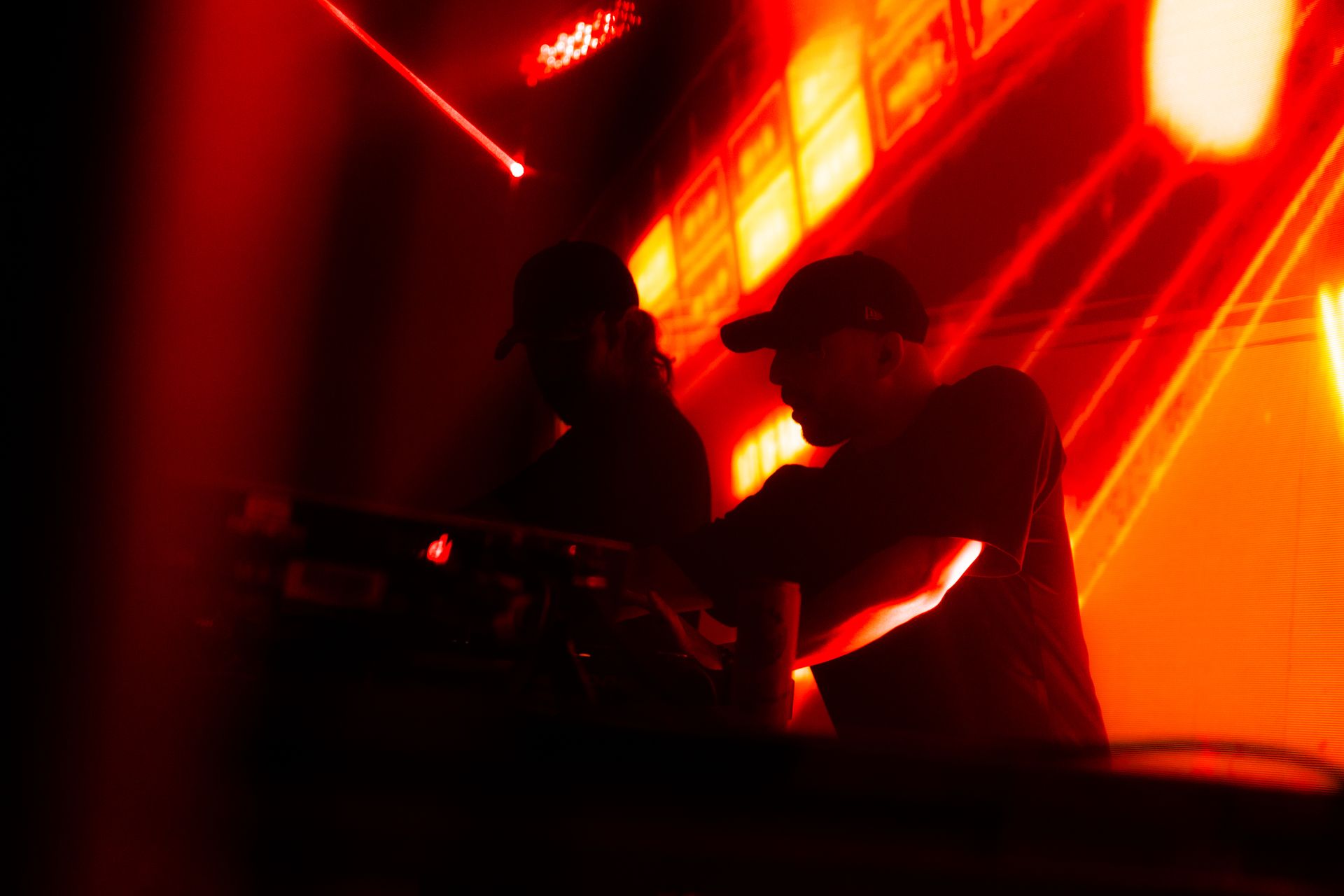 A man is playing a dj set in a dark room with red lights.