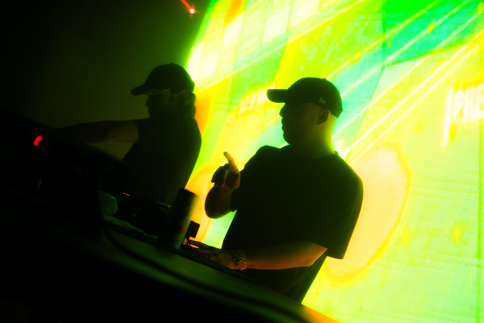 Two men are playing music in front of a colorful background.