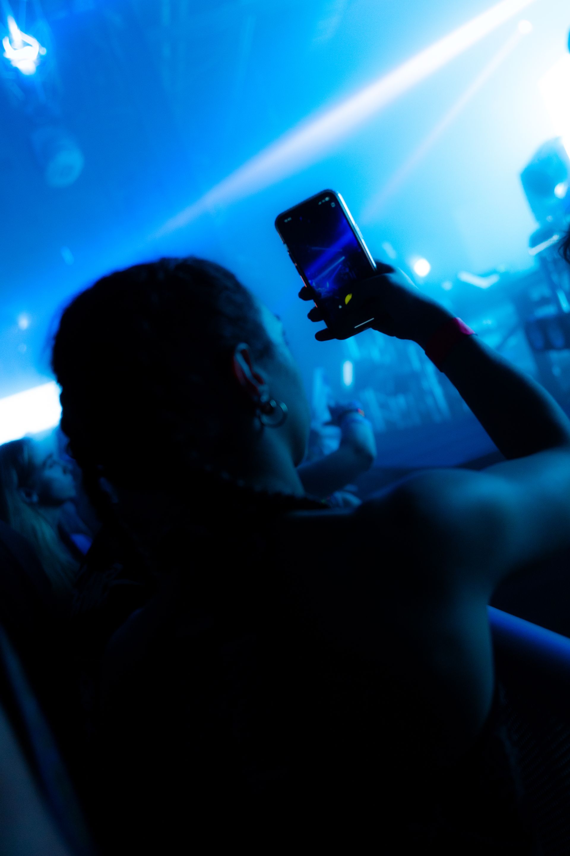 A person is taking a picture with their phone at a concert.