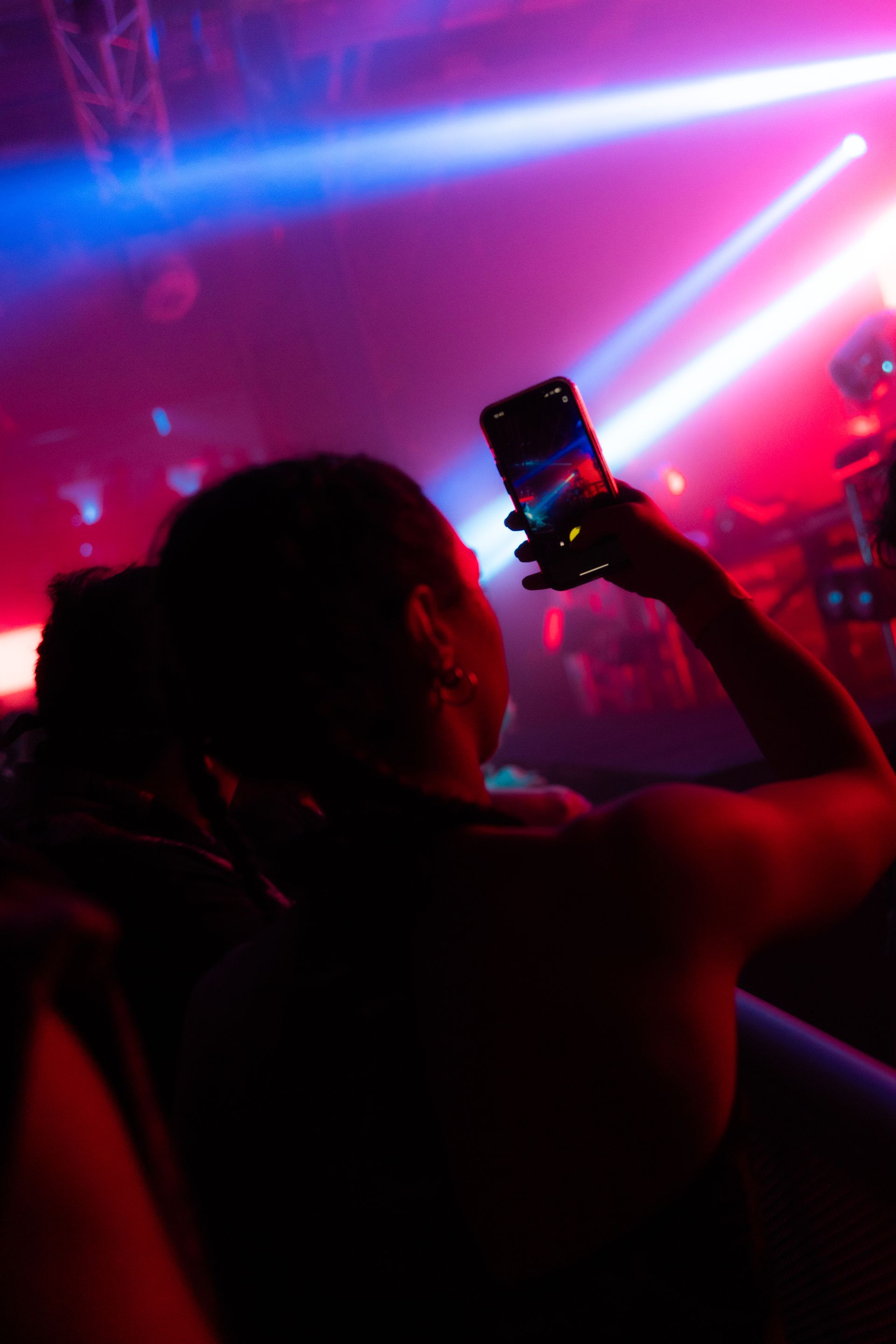 A woman is taking a picture of herself in a club with her phone.