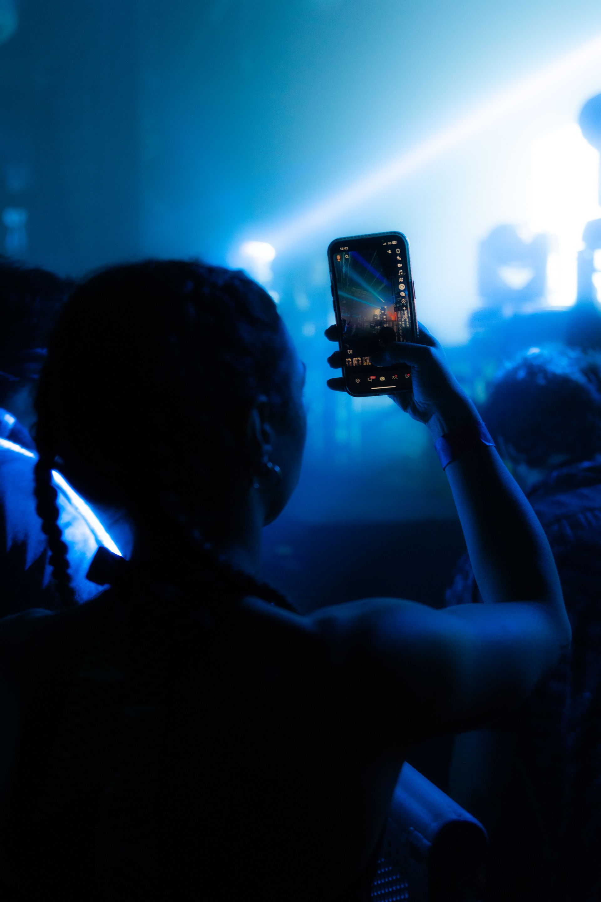 A woman is taking a picture of a concert with her cell phone.