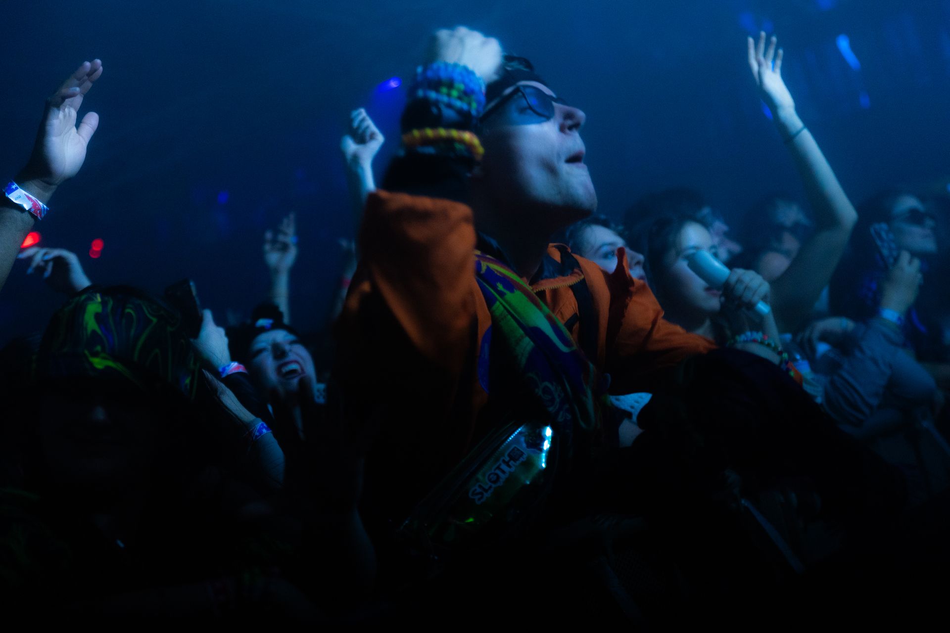 A group of people are standing in a dark room with their hands in the air.