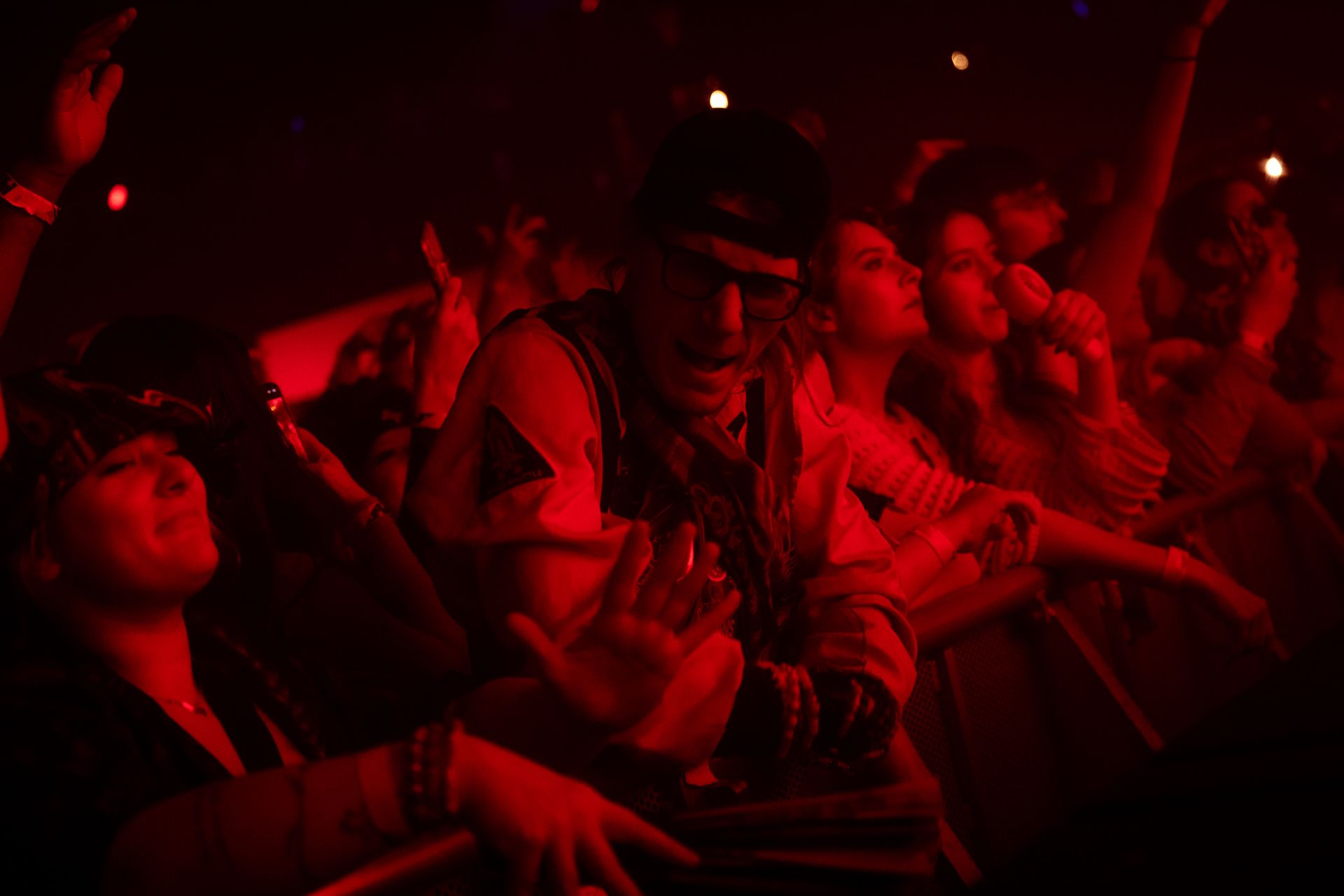 A crowd of people are sitting in a dark room with their hands in the air.