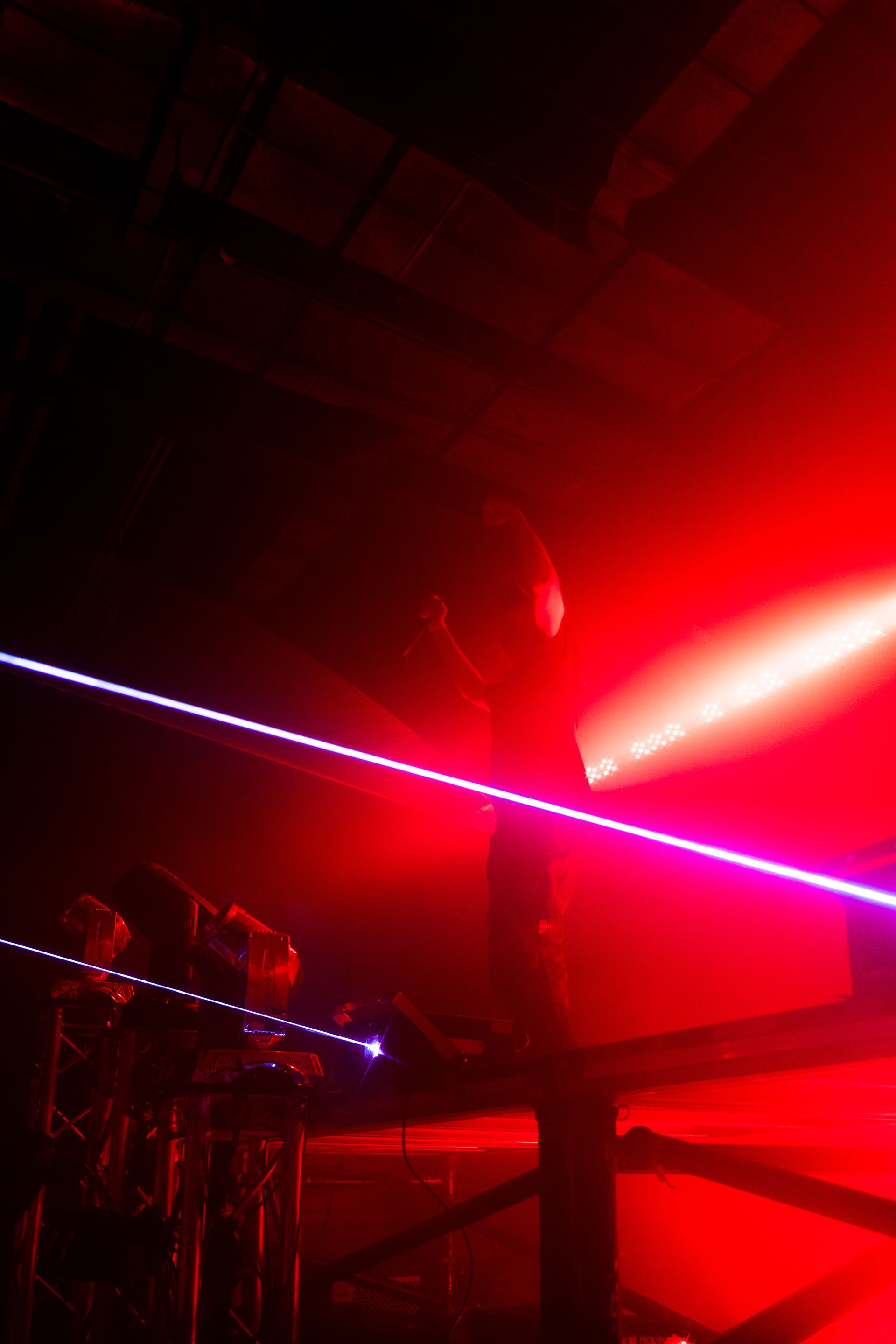 A person is standing in a dark room with red lights behind them