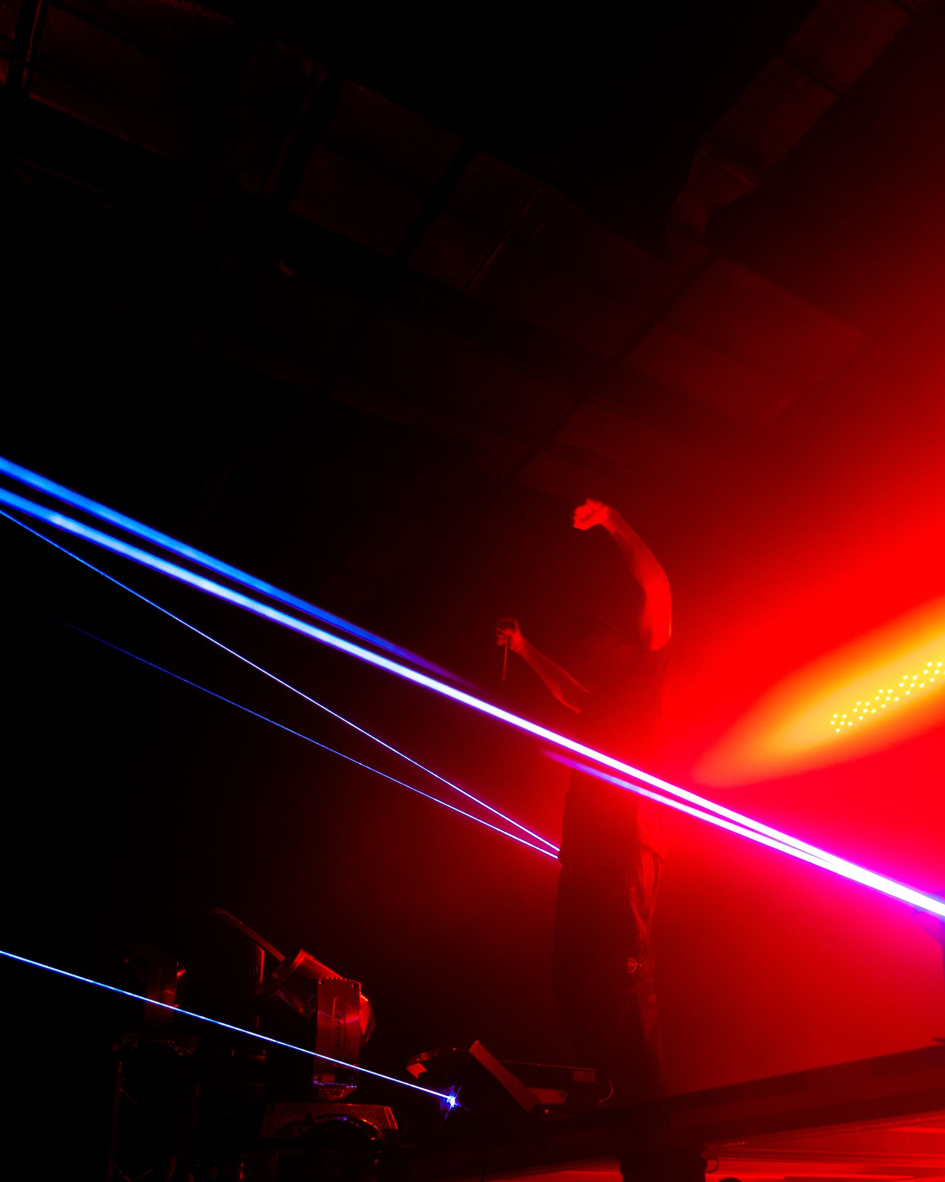 A person is dancing in a dark room with red and blue lights