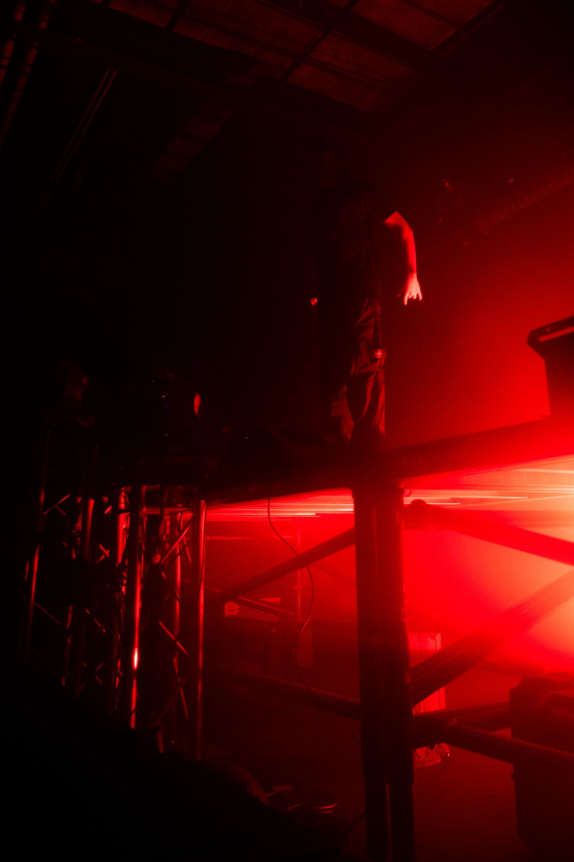 A person is standing in a dark room with red lights.