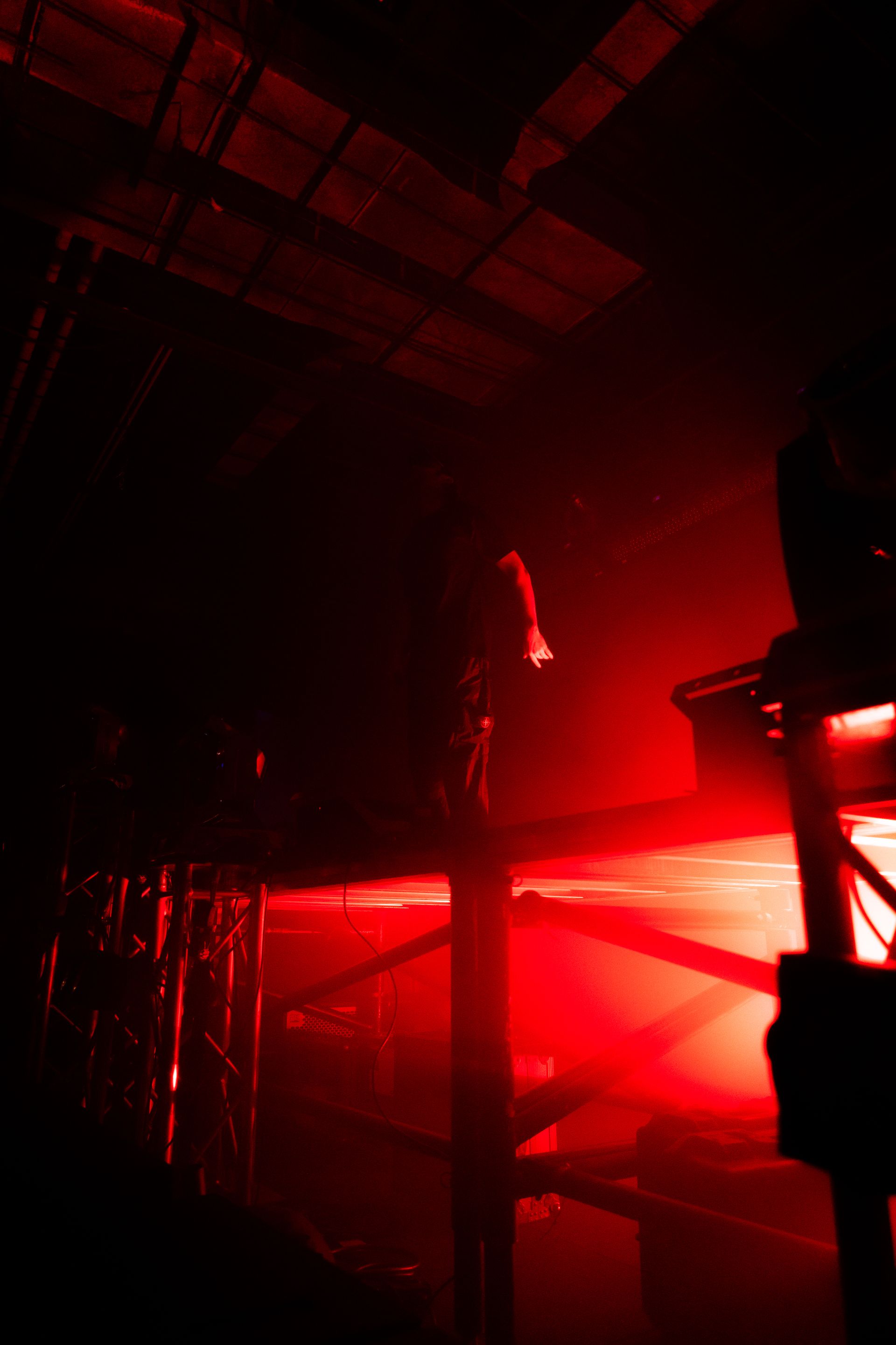 A person is standing on a stage in a dark room with red lights.