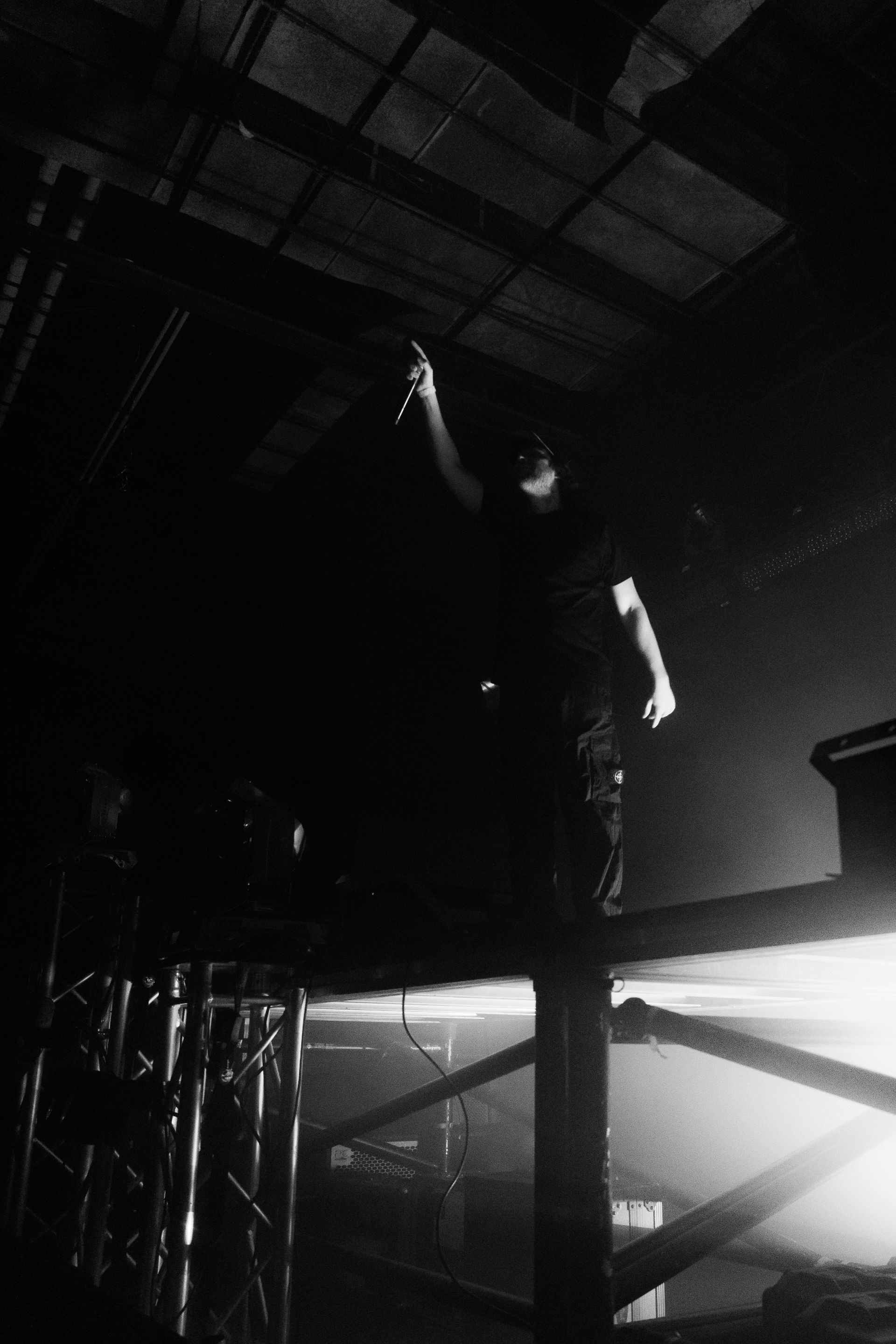 A man is standing on a stage in a dark room holding a microphone.