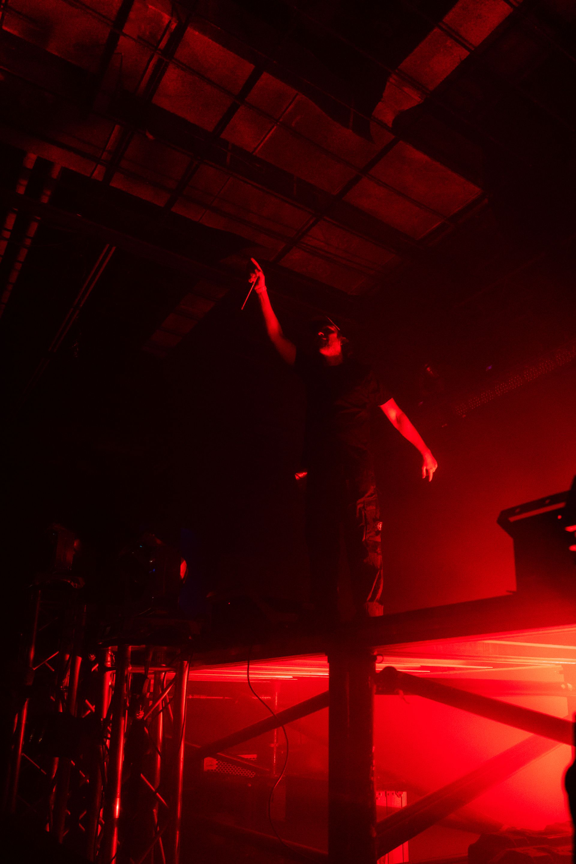 A man is standing on a stage in a dark room with red lights.