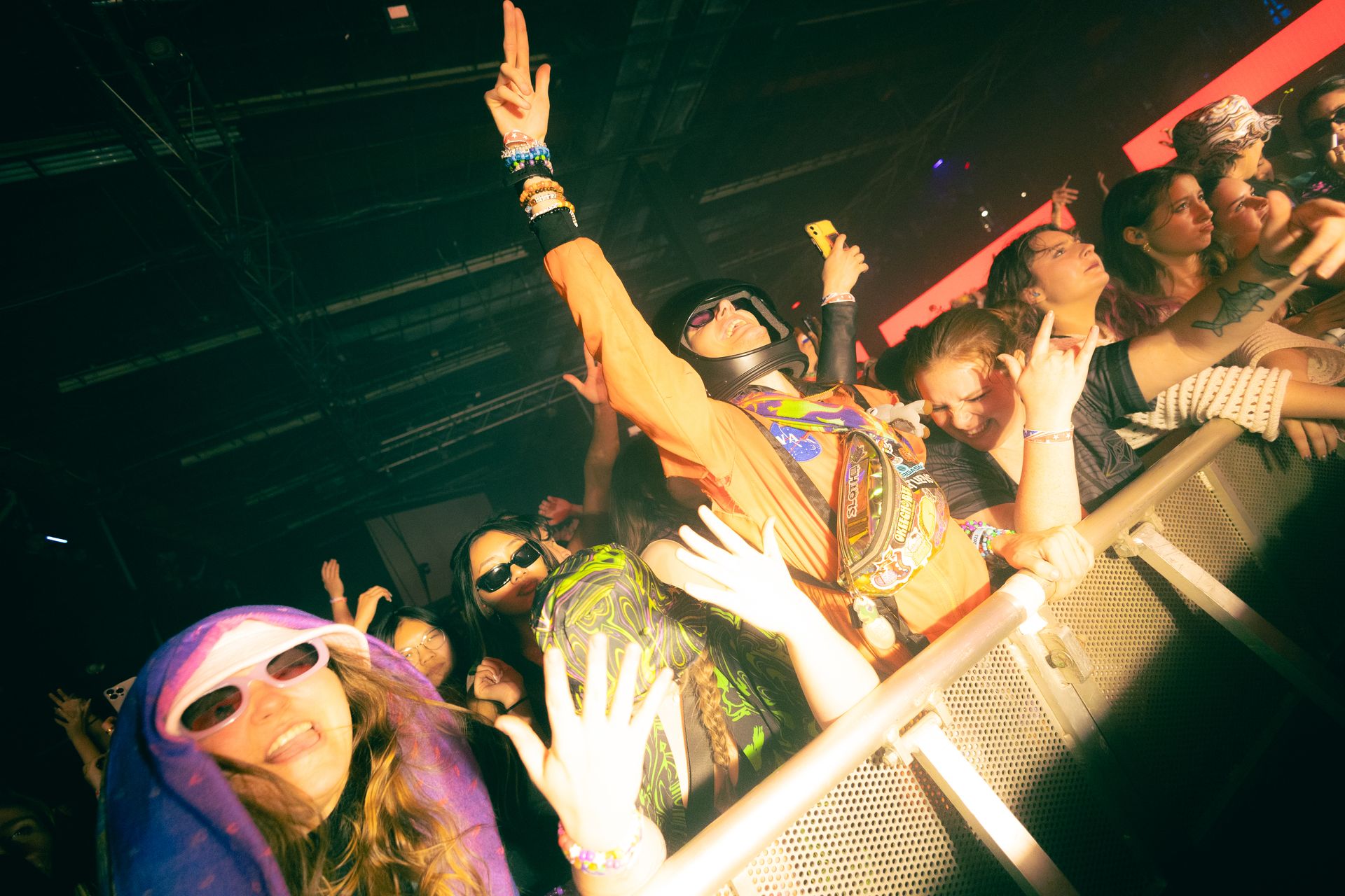 A crowd of people at a concert with their hands in the air