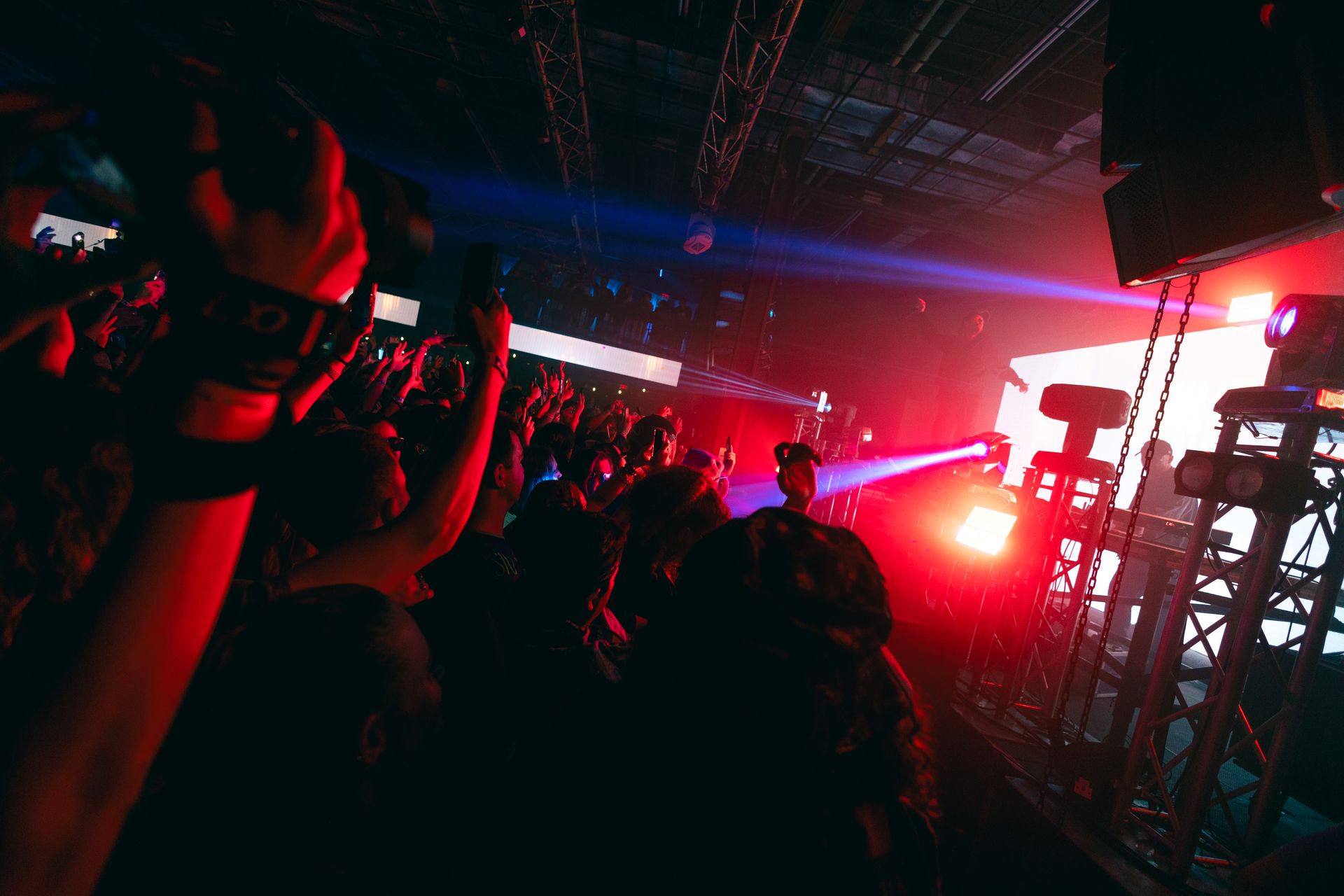 A crowd of people are standing in a dark room at a concert.