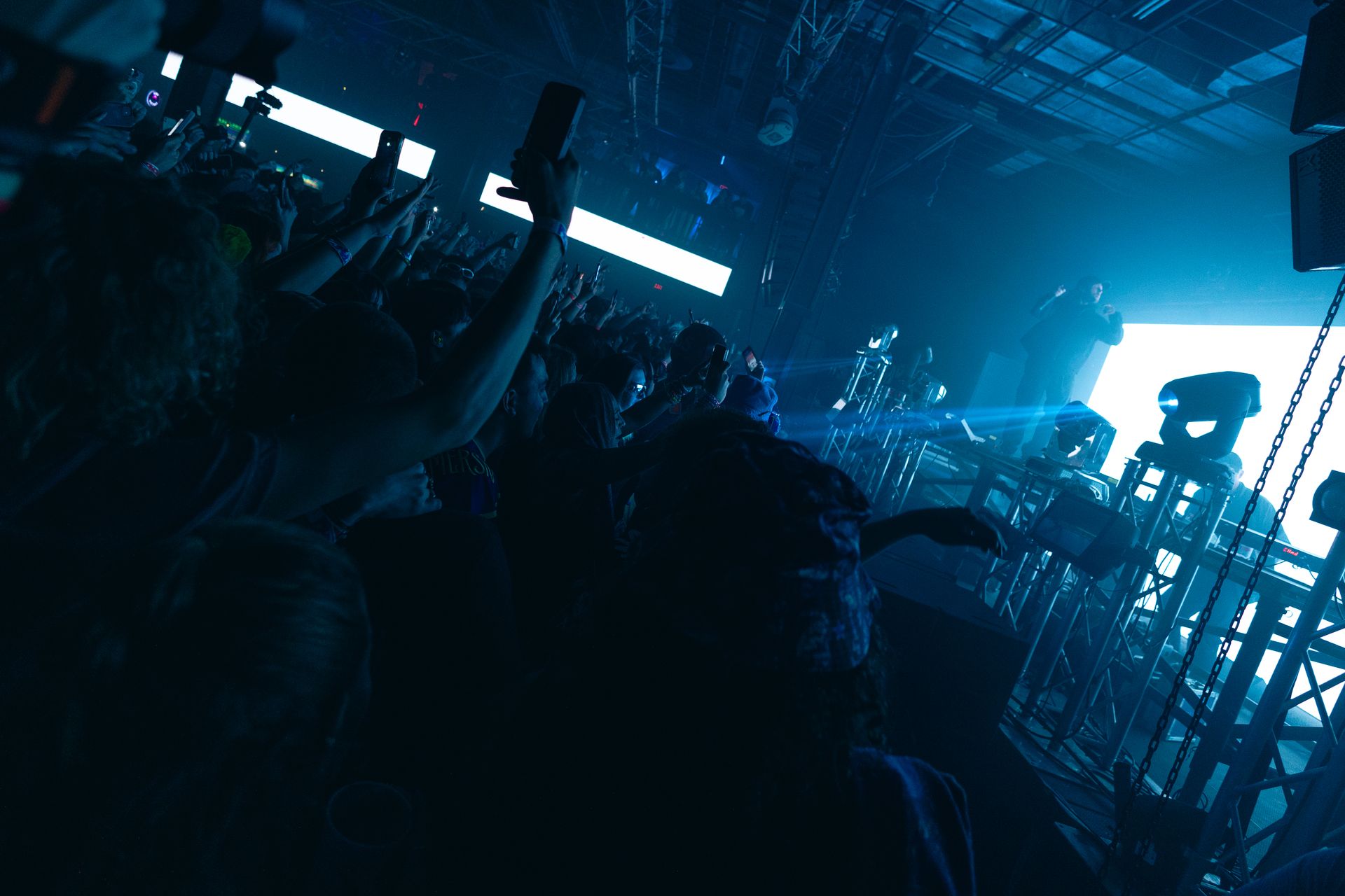 A crowd of people at a concert with their hands in the air