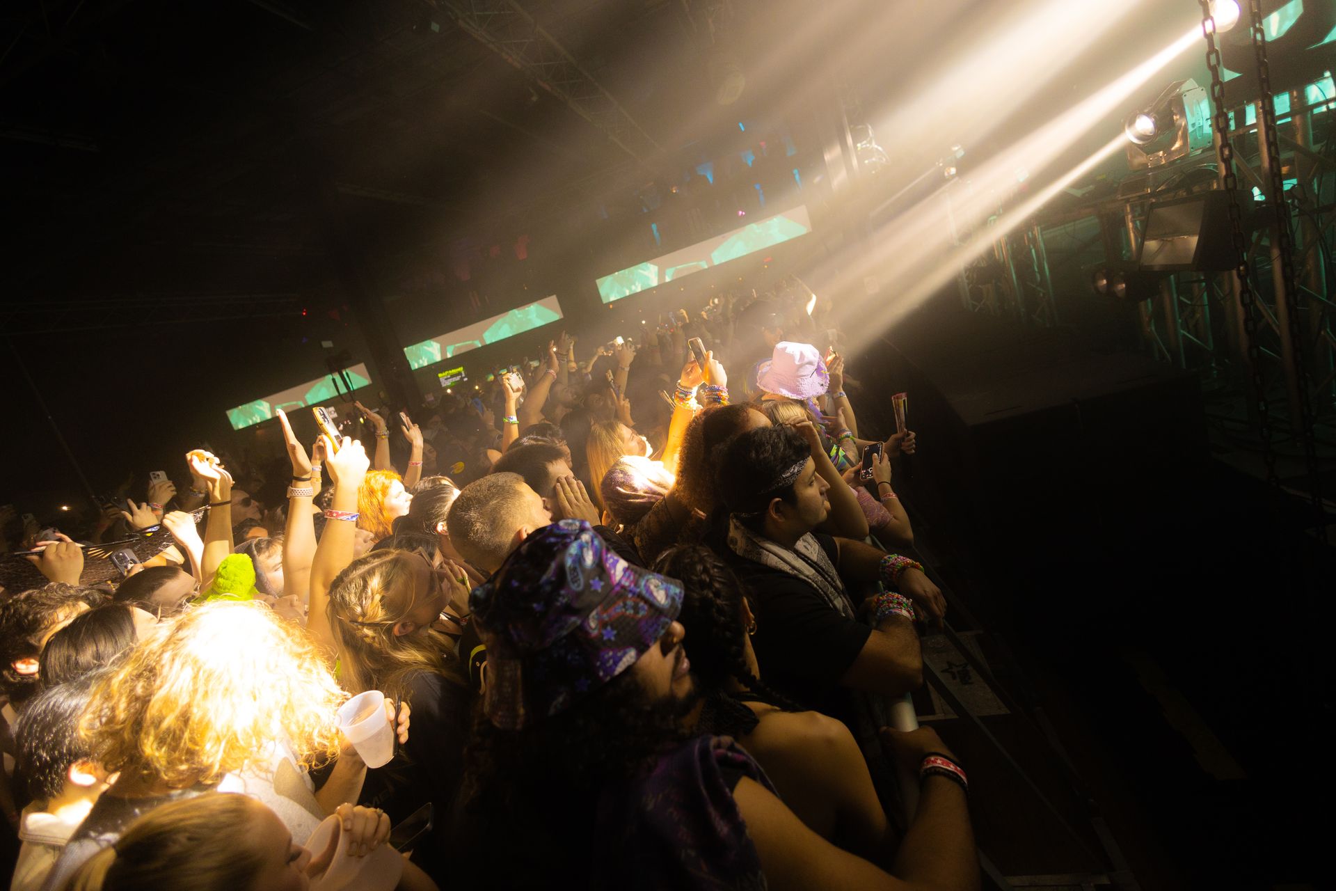 A crowd of people are watching a concert in a dark room.