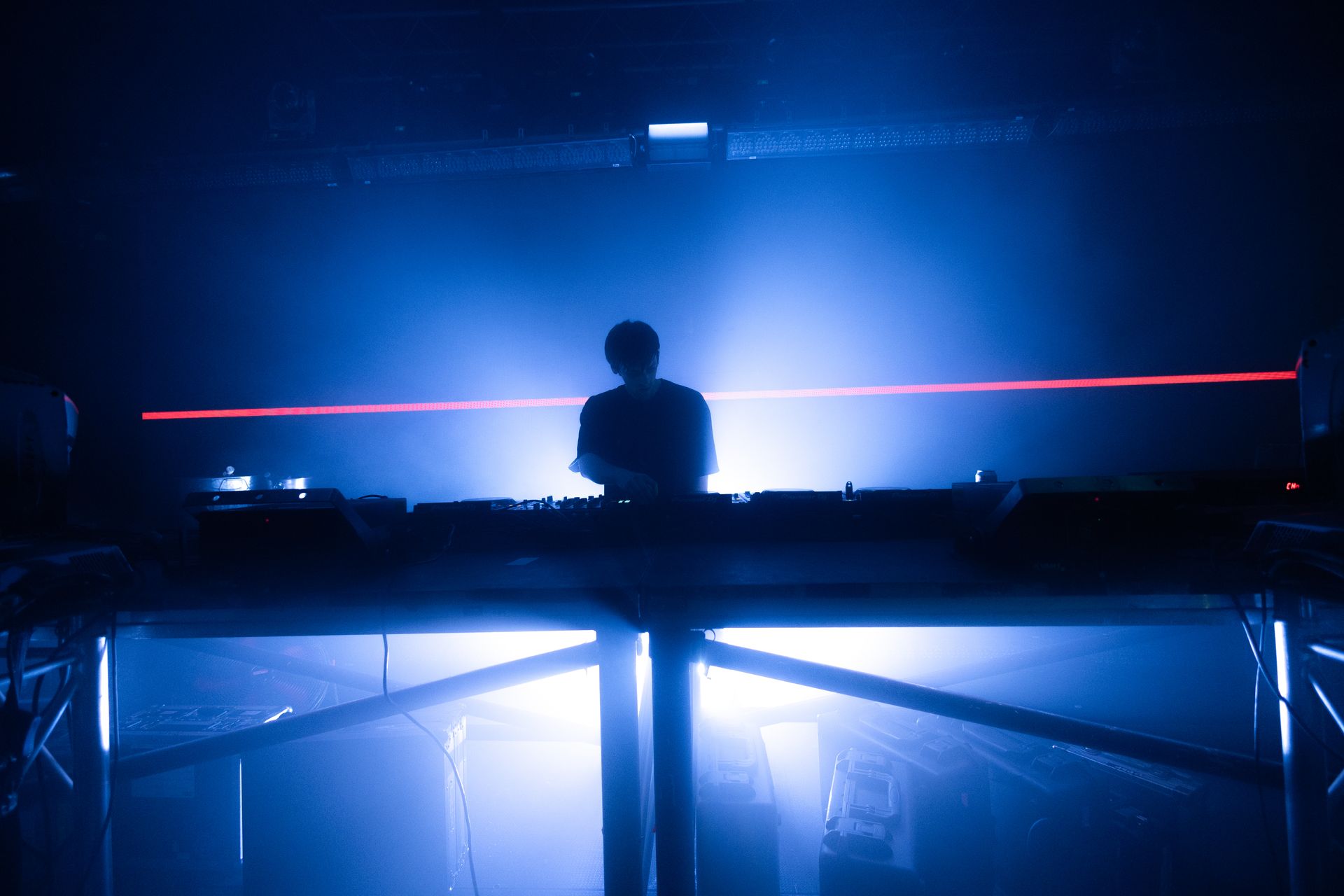 A dj is playing music on a stage in a dark room.