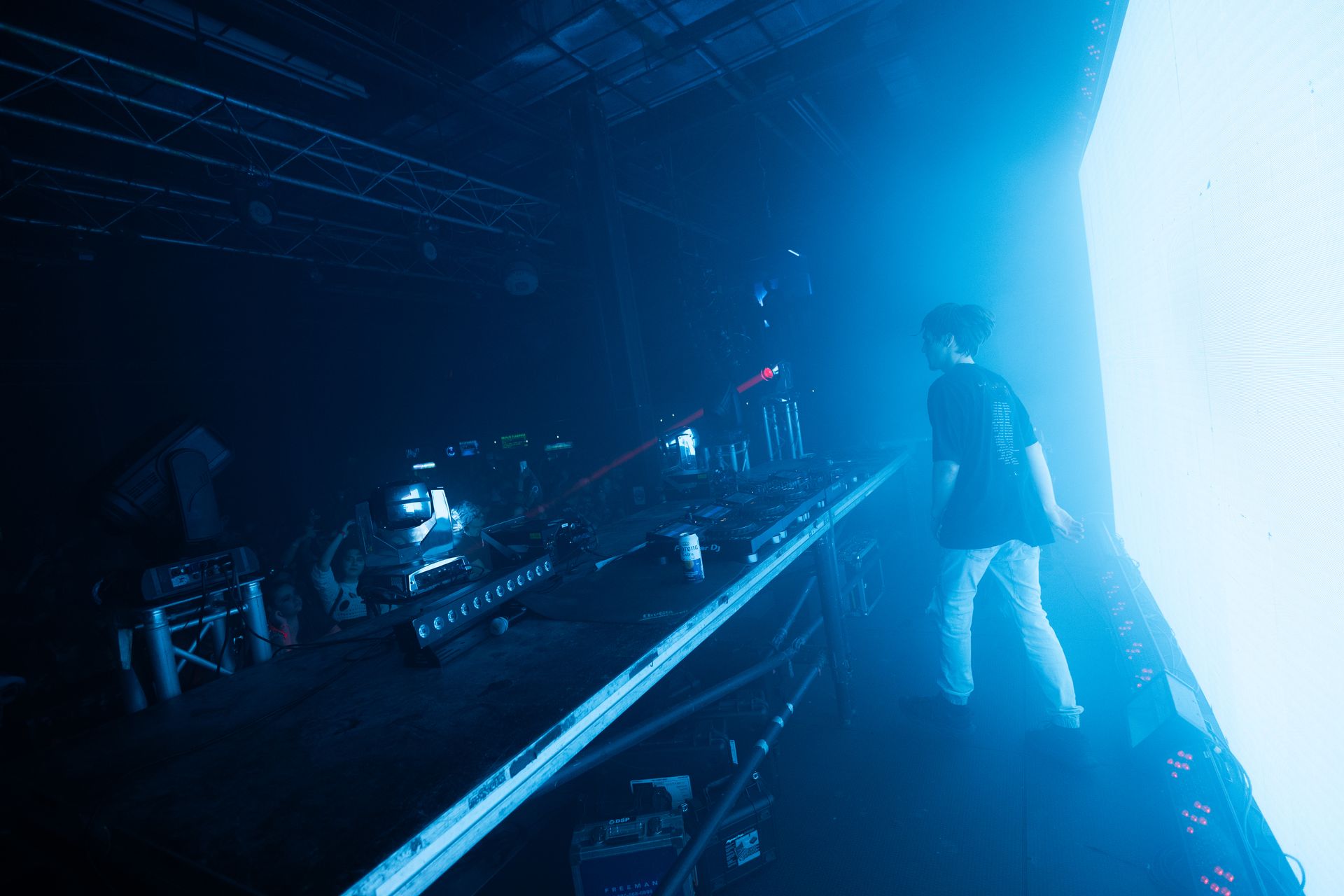 A man is standing on a stage in a dark room with a blue light behind him.