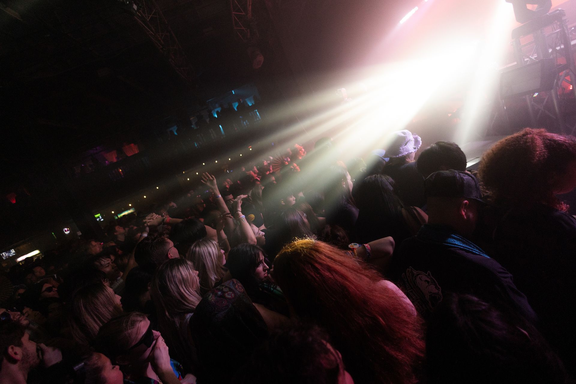 A crowd of people are watching a concert in a dark room.