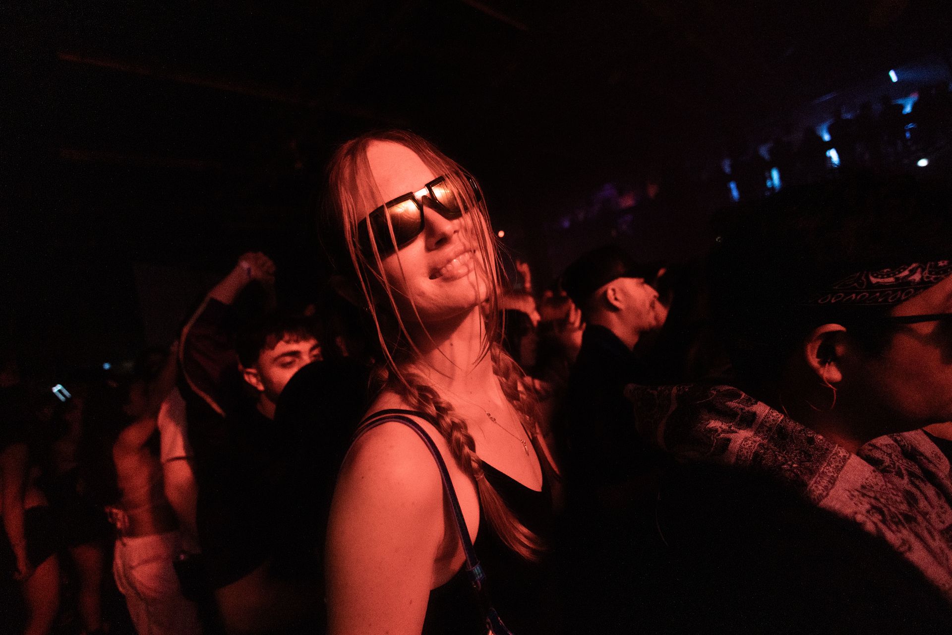 A woman wearing sunglasses is dancing in a crowd of people at a party.