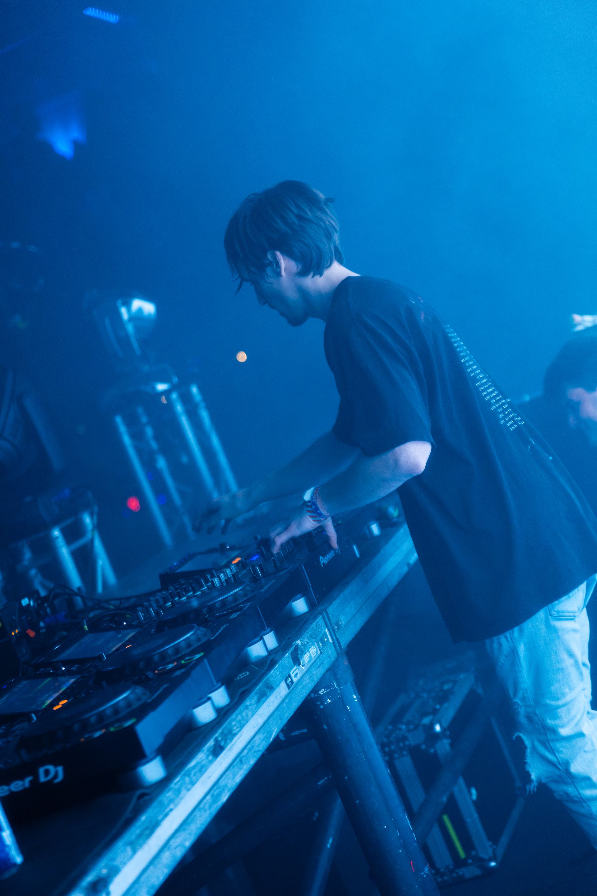 A man is playing a dj set in a dark room.