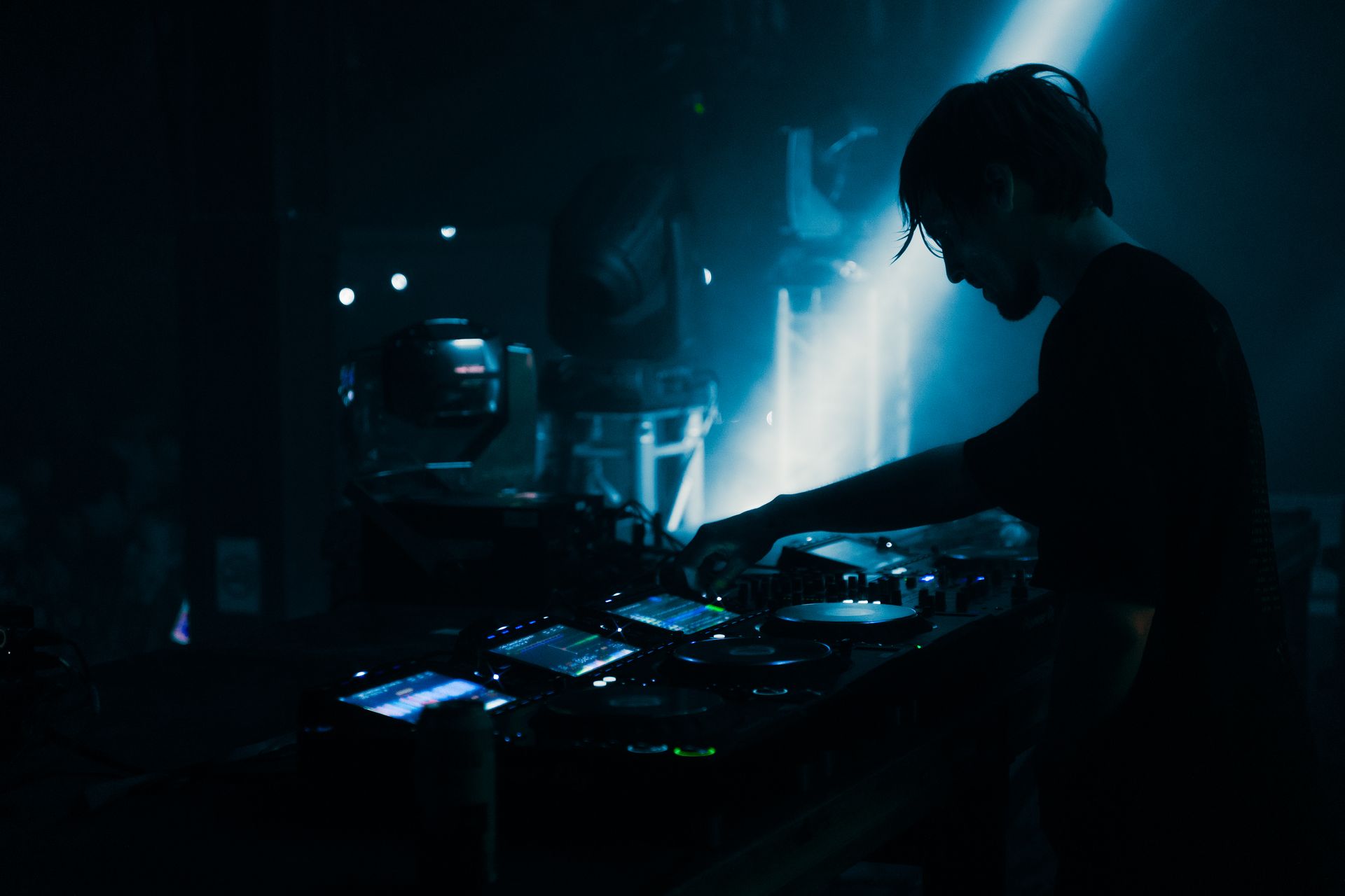 A man is playing a dj set in a dark room.