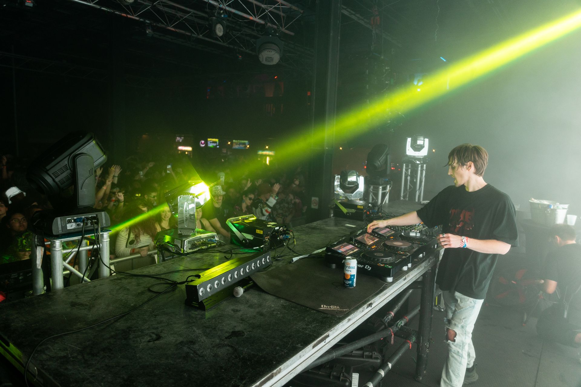A man is playing a dj set on a stage in front of a crowd.