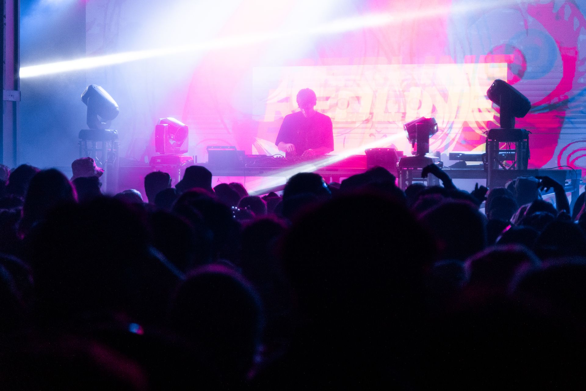 A crowd of people are watching a dj perform on stage at a concert.