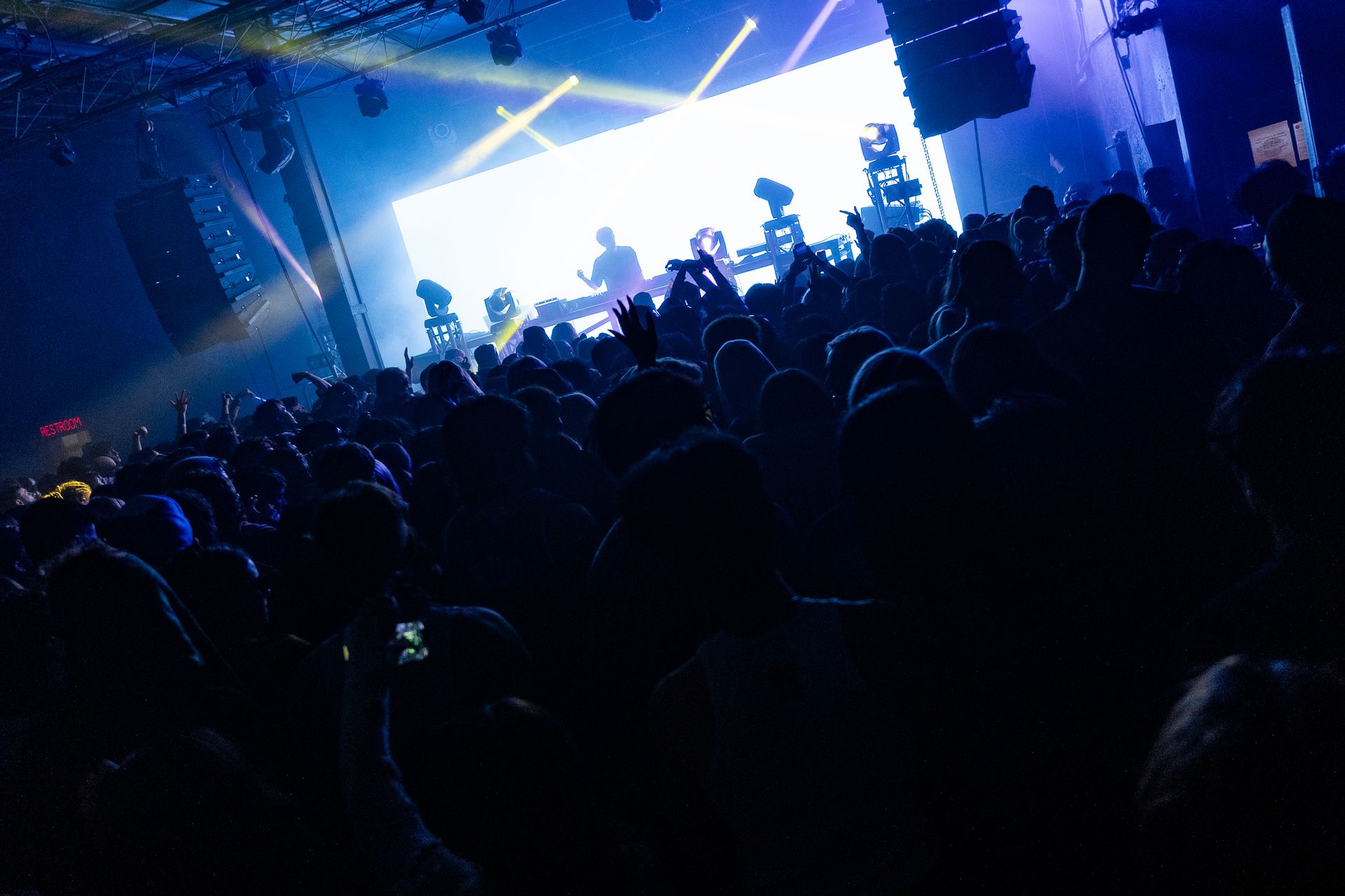 A crowd of people are sitting in front of a stage at a concert.