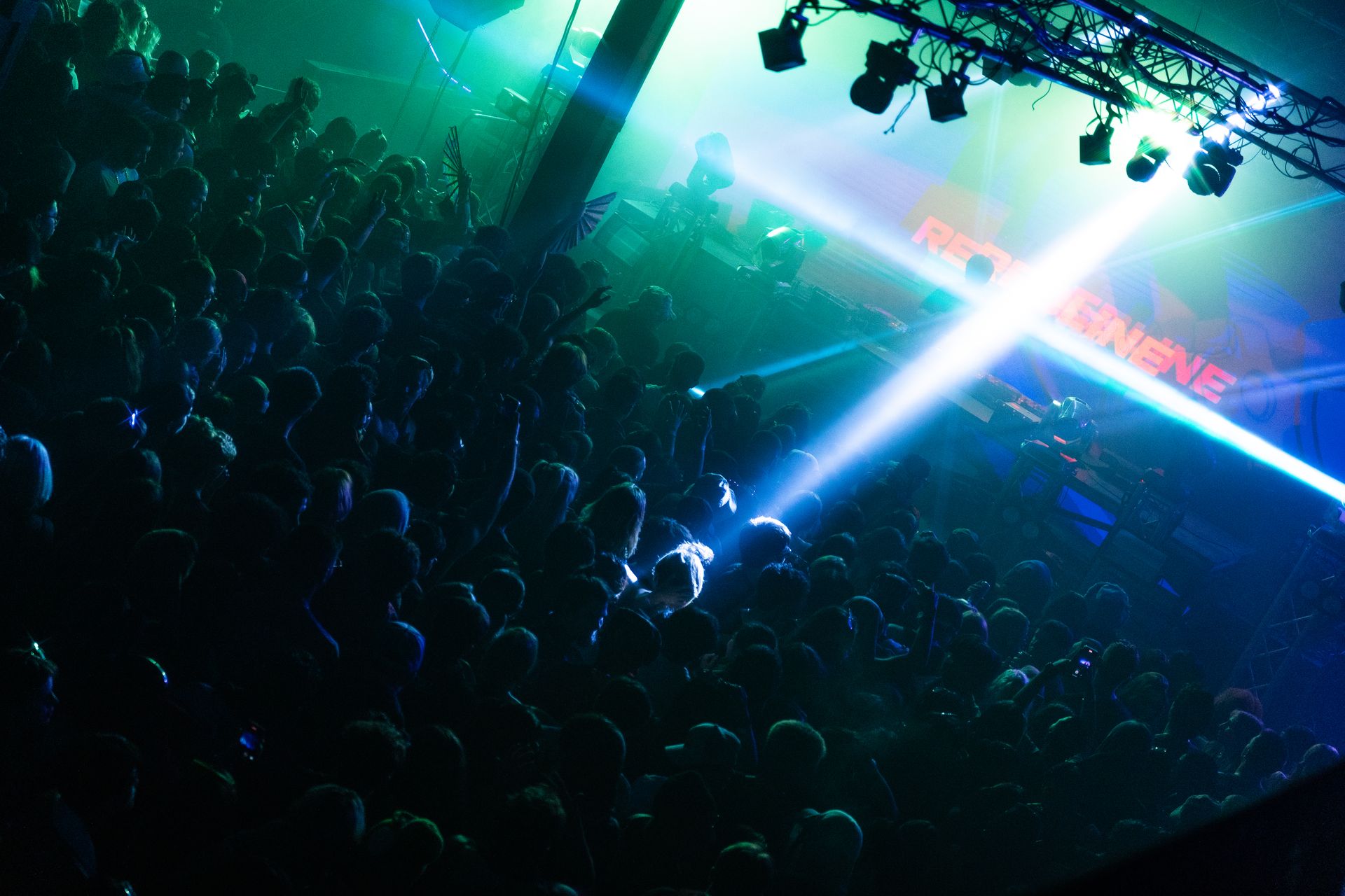 A crowd of people are gathered in a dark room at a concert