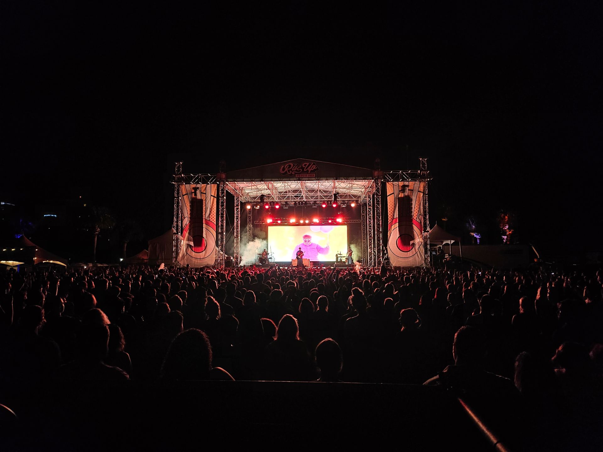 A crowd of people are watching a concert at night.